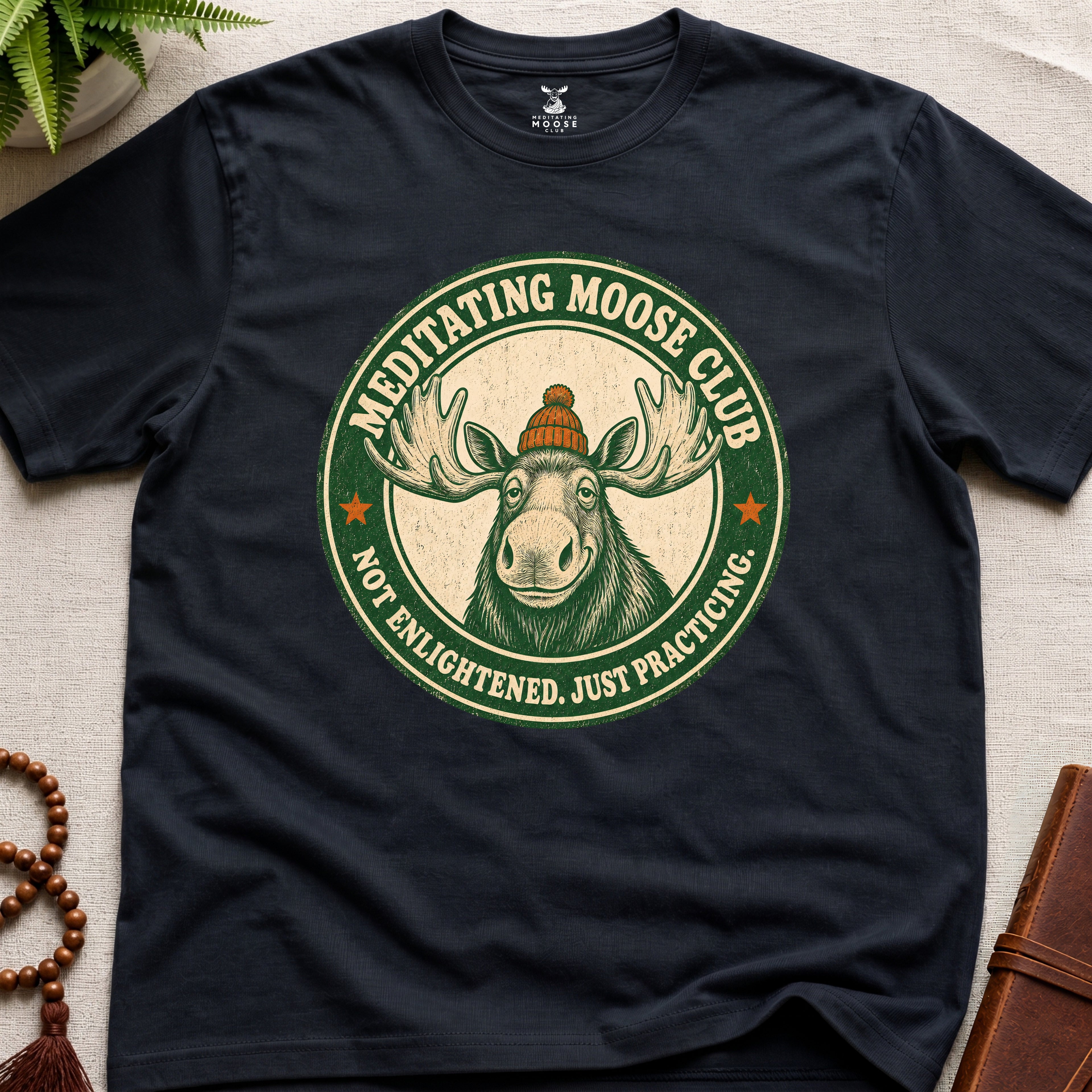 Black mindfulness t-shirt mockup featuring Meditating Moose Club signature moose logo graphic