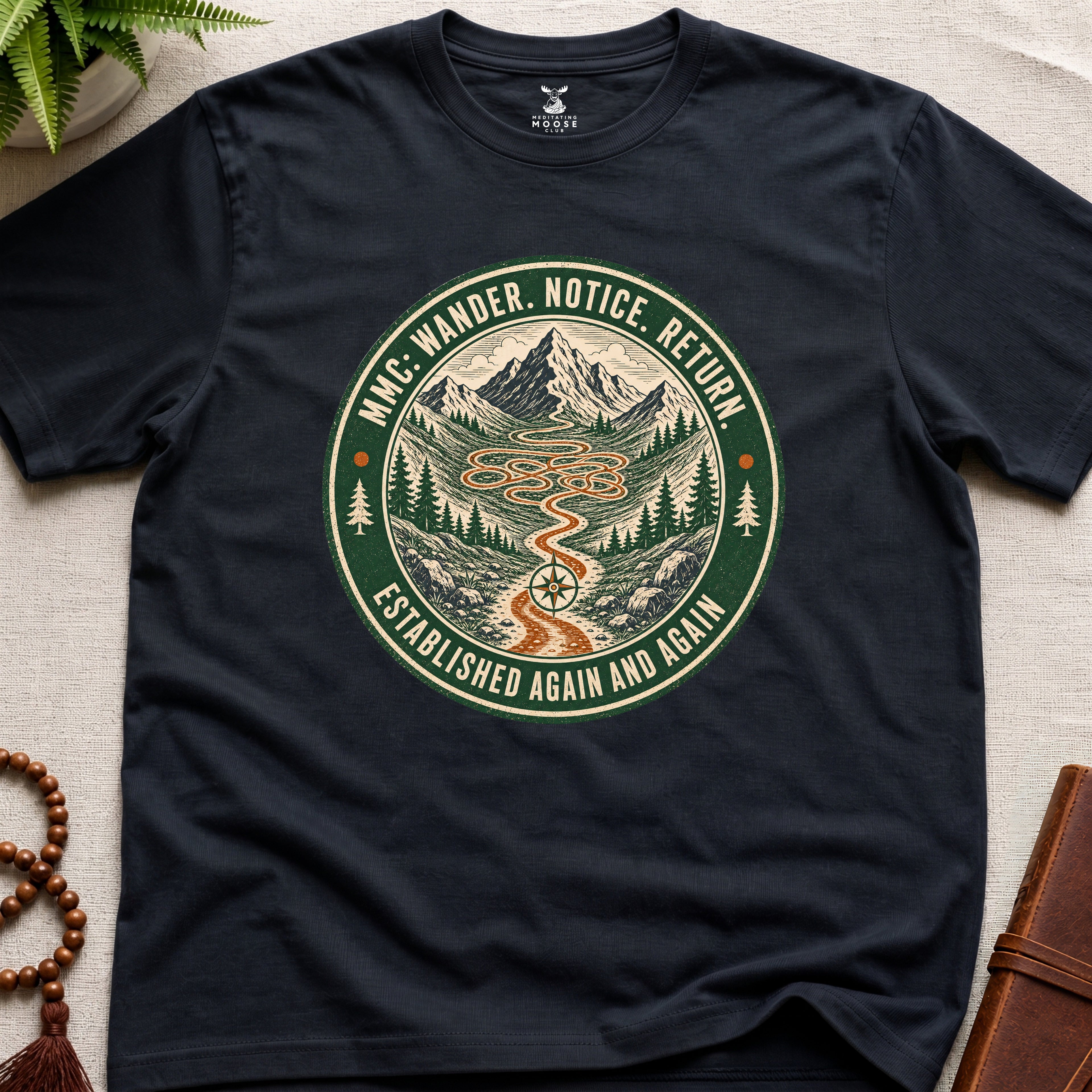 Black mindfulness t-shirt mockup featuring Meditating Moose Club Wander Notice Return mountain trail badge graphic