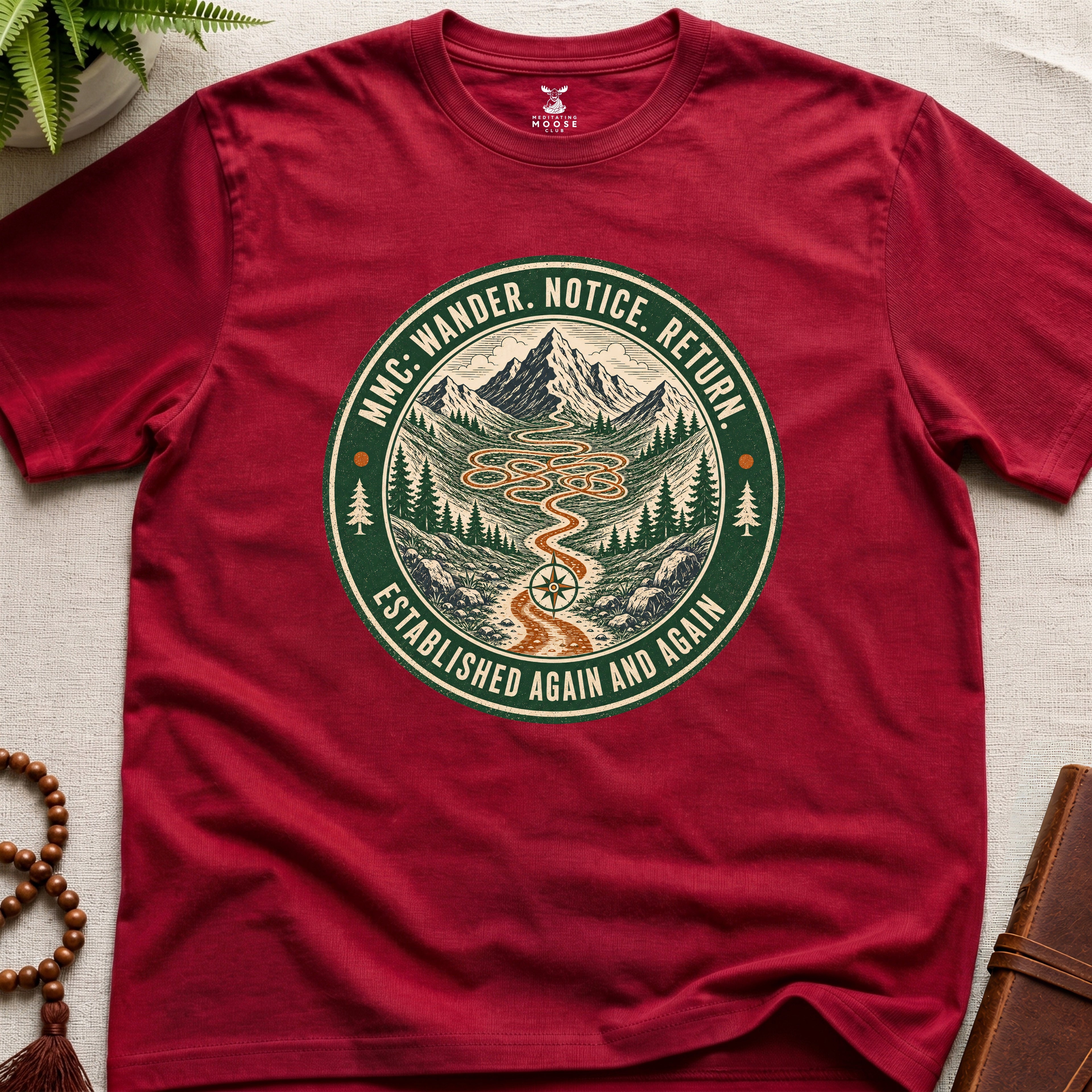 Red mindfulness t-shirt mockup featuring Meditating Moose Club Wander Notice Return mountain trail badge graphic