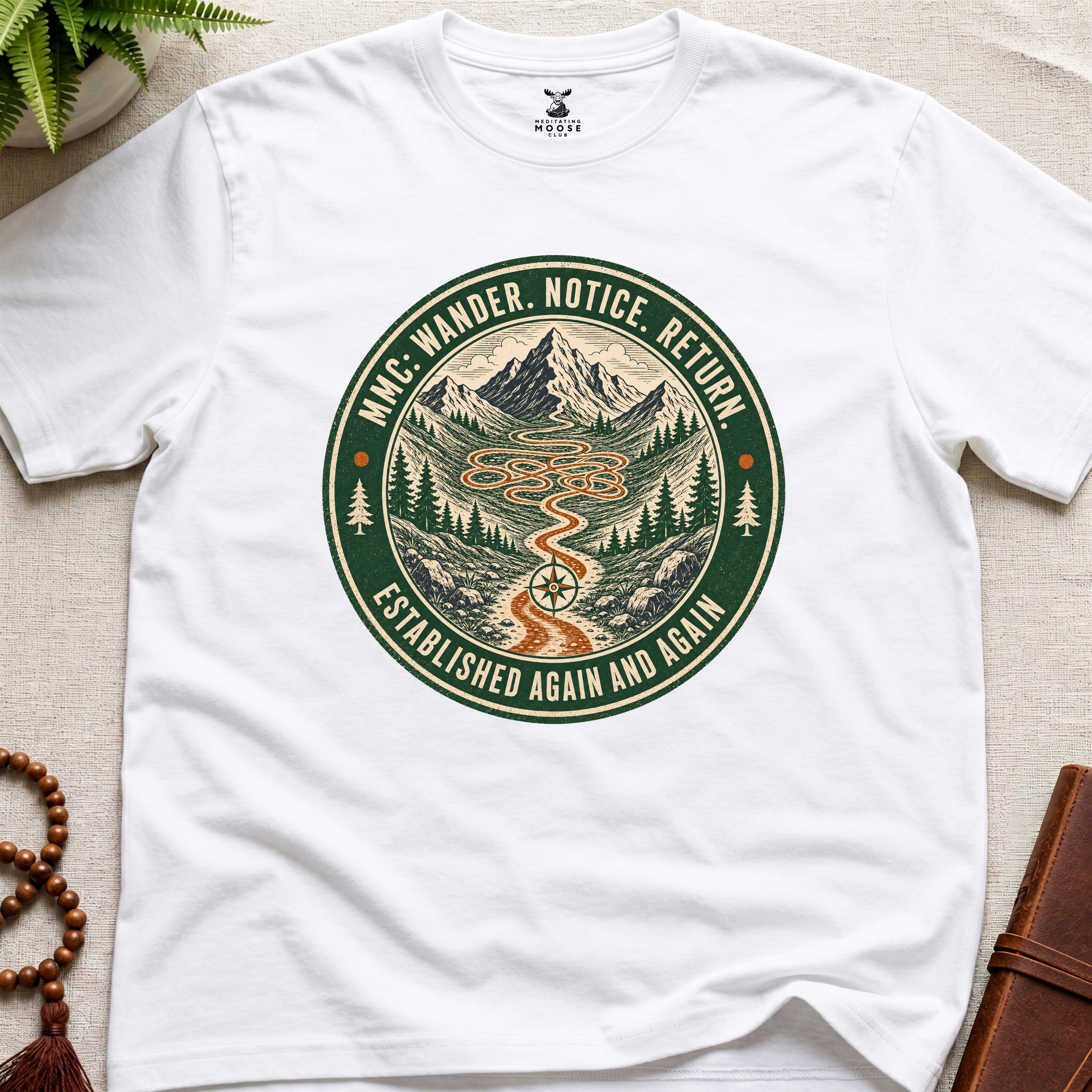 White mindfulness t-shirt mockup featuring Meditating Moose Club Wander Notice Return mountain trail badge graphic