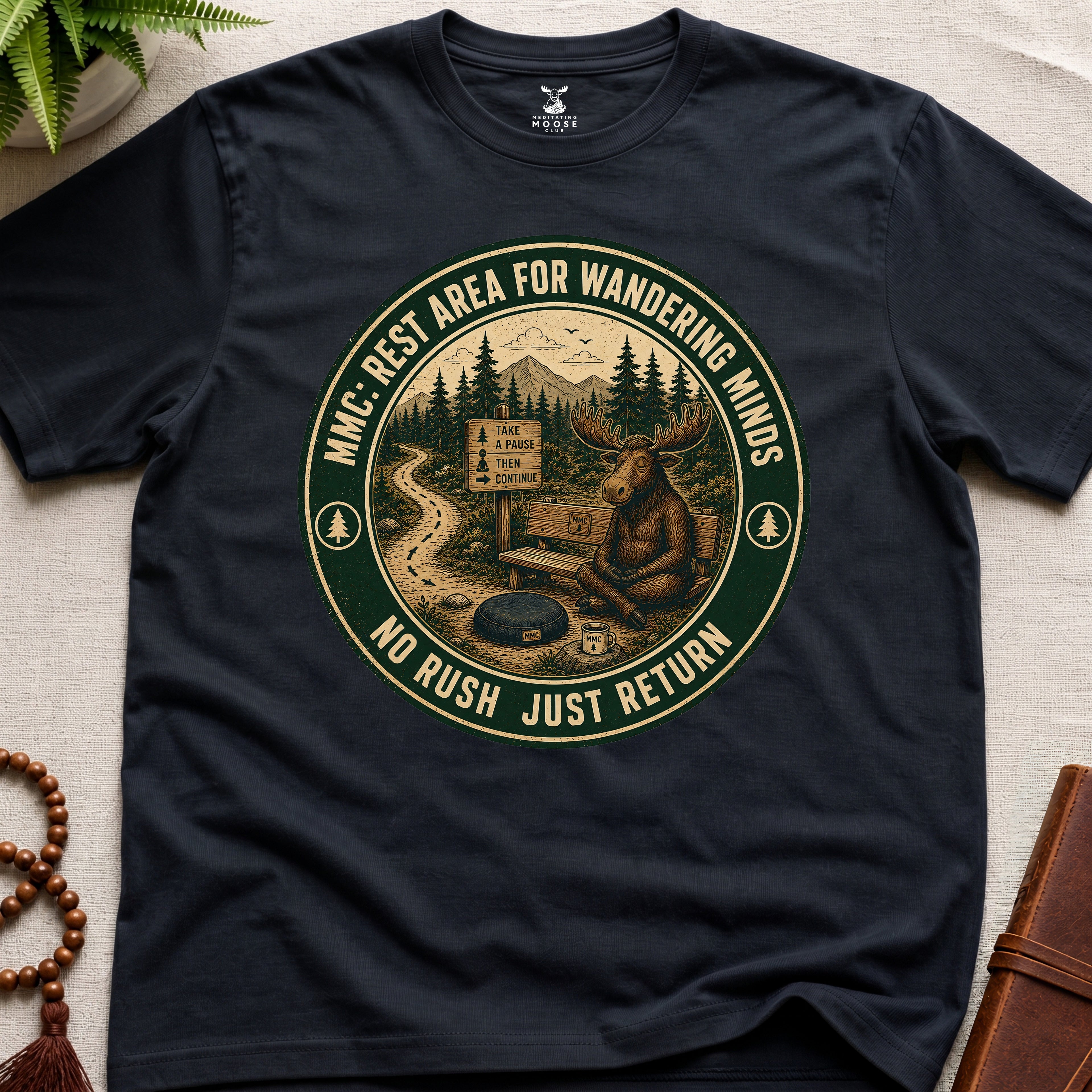 Black funny mindfulness t-shirt mockup featuring Rest Area for Wandering Minds meditating moose vintage badge design