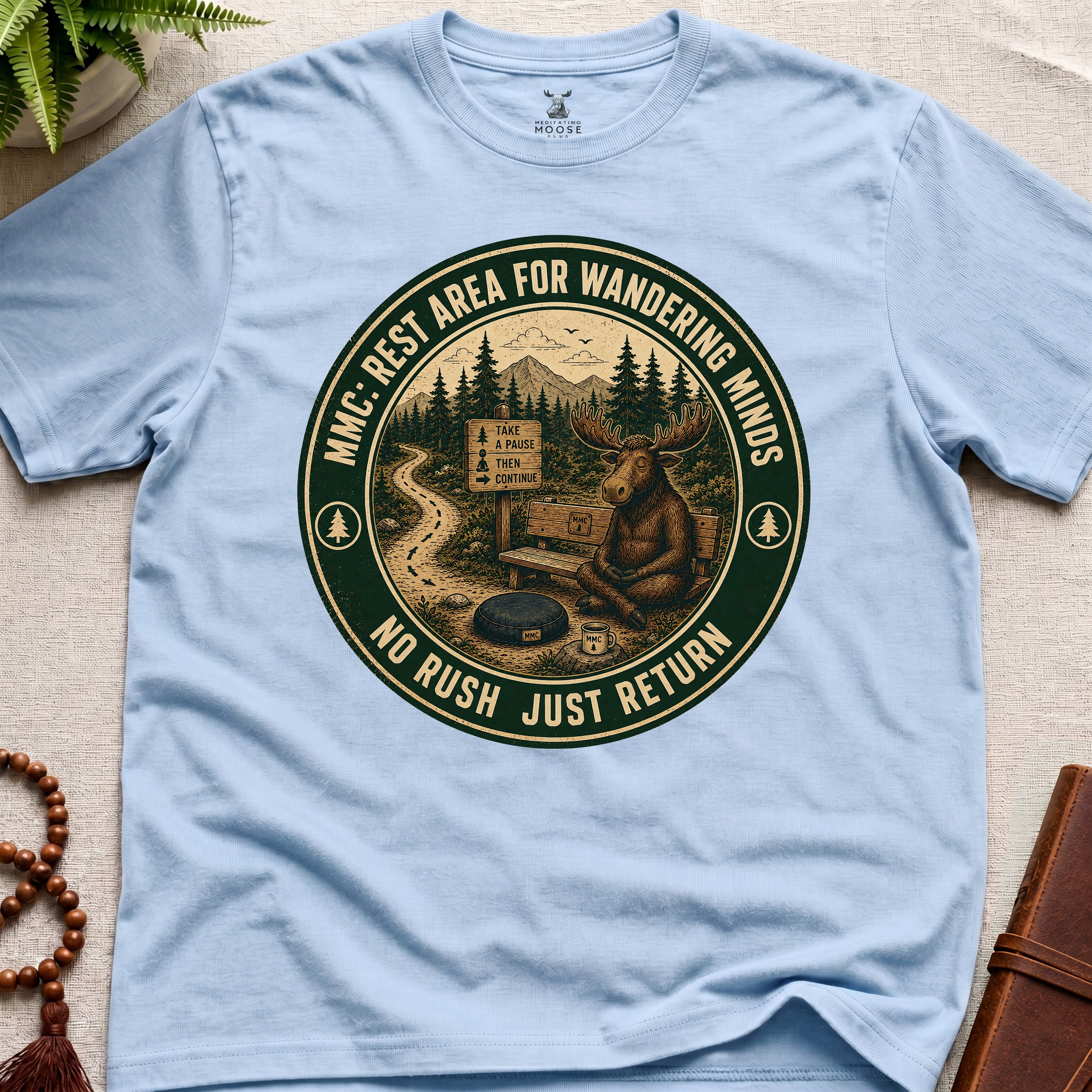 Light blue funny mindfulness t-shirt mockup featuring Rest Area for Wandering Minds meditating moose vintage badge design