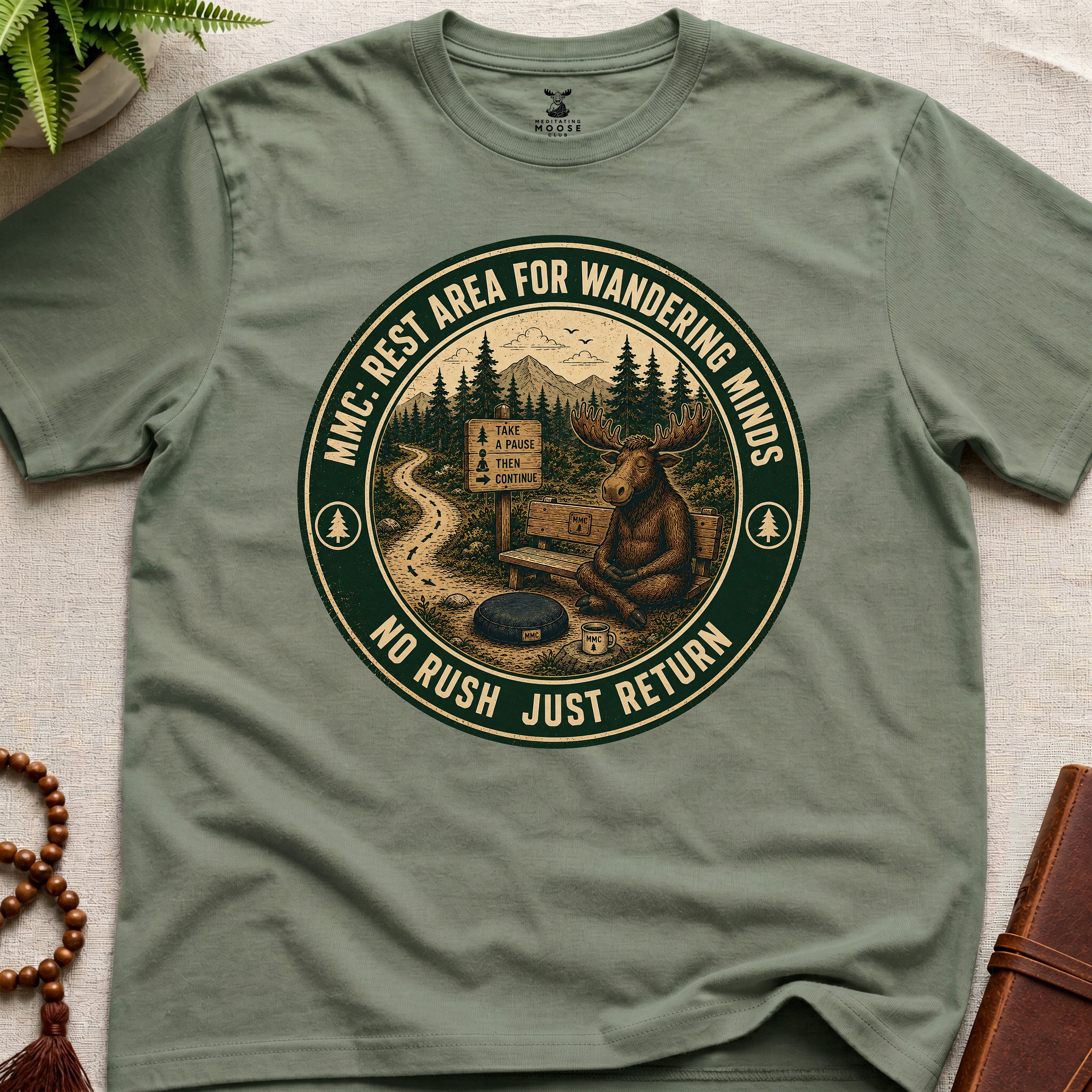 Green funny mindfulness t-shirt mockup featuring Rest Area for Wandering Minds meditating moose vintage badge design
