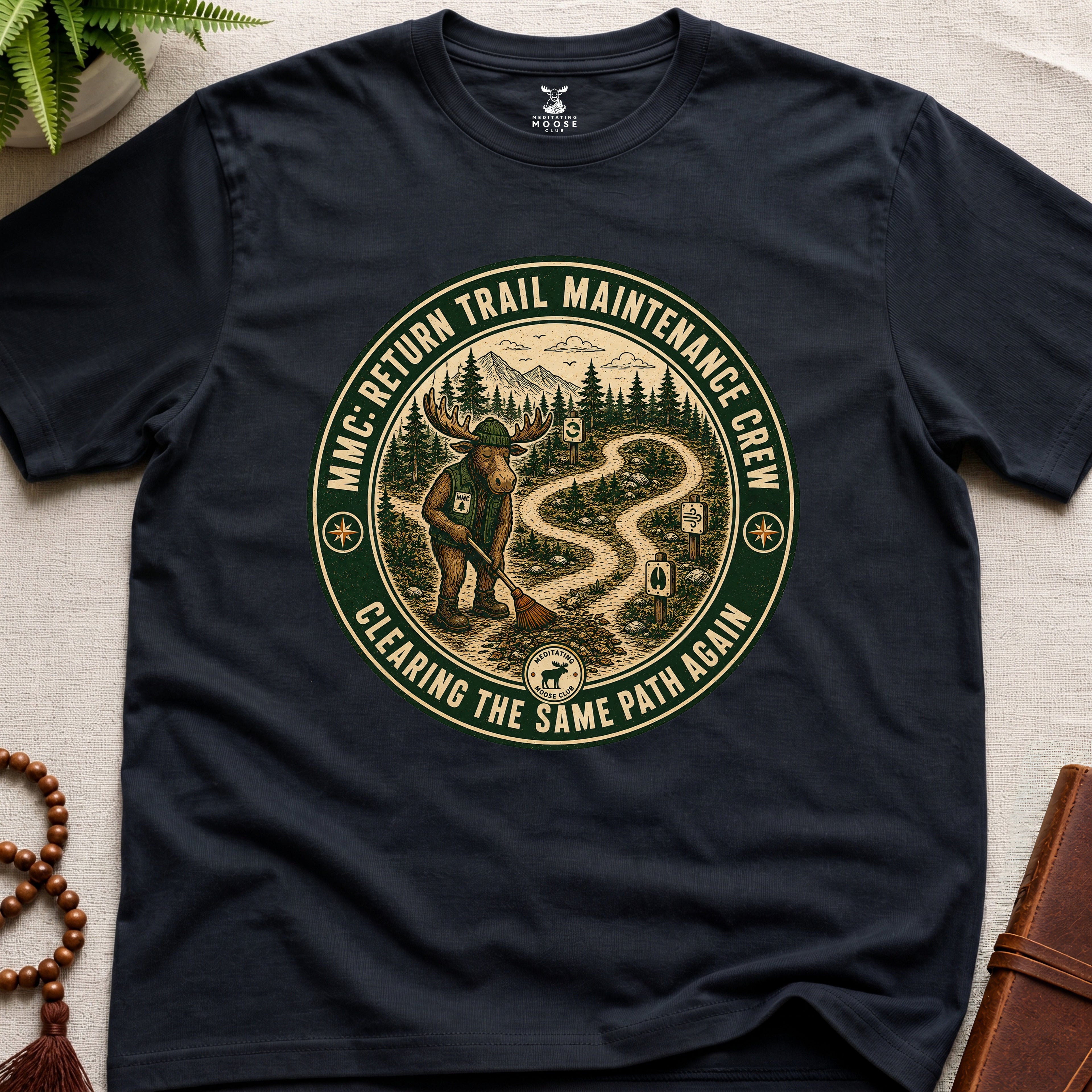 Black mindfulness t-shirt mockup featuring Return Trail Maintenance Crew meditating moose vintage badge graphic