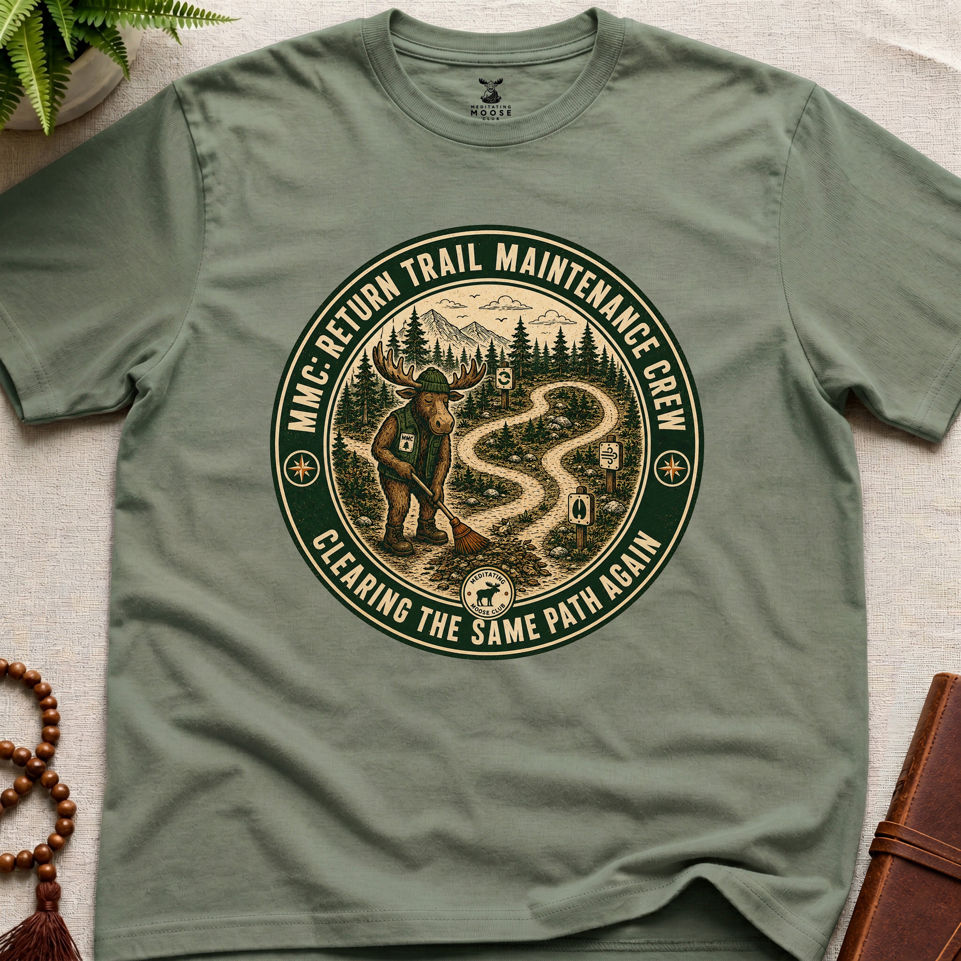 Green mindfulness t-shirt mockup featuring Return Trail Maintenance Crew meditating moose vintage badge graphic