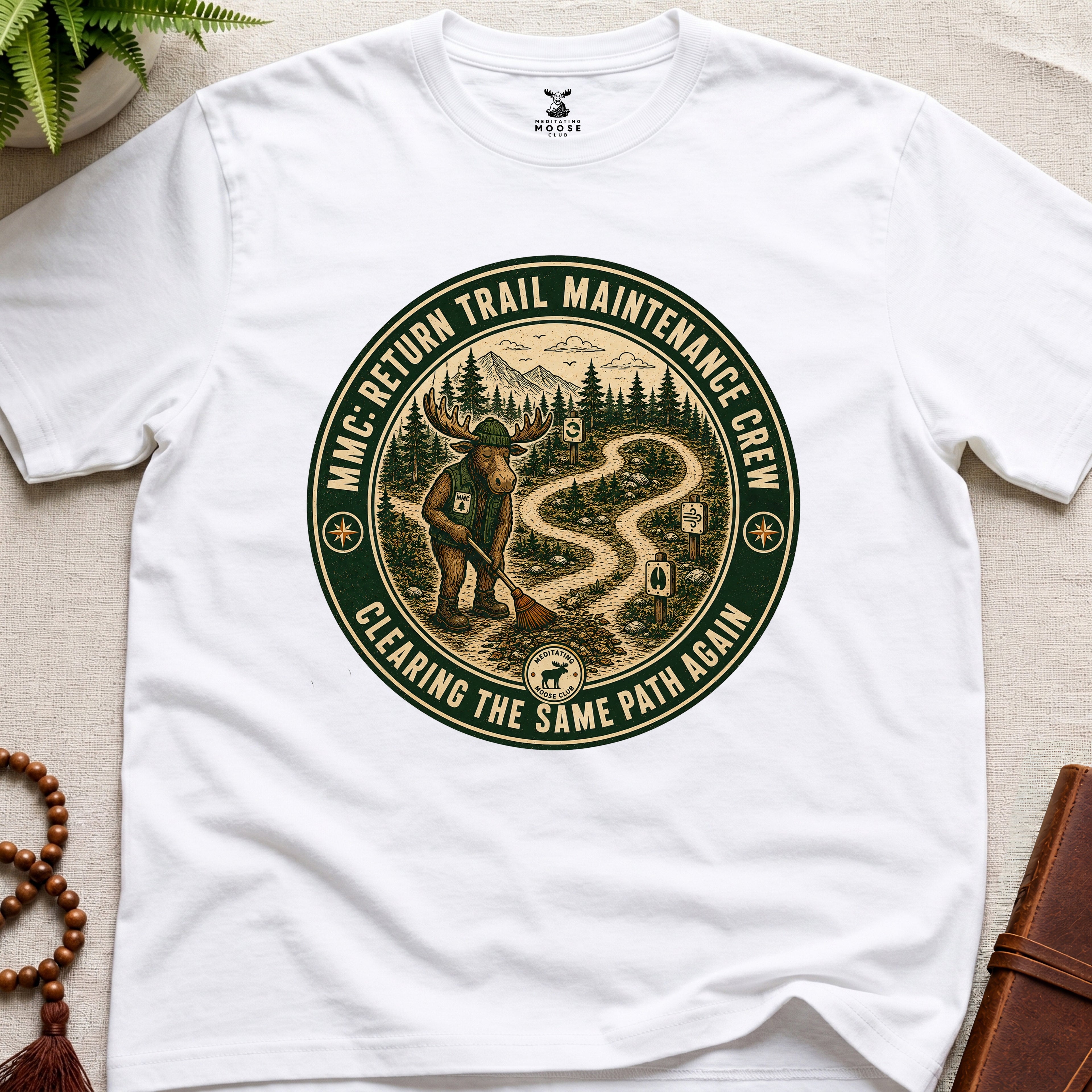 White mindfulness t-shirt mockup featuring Return Trail Maintenance Crew meditating moose vintage badge graphic