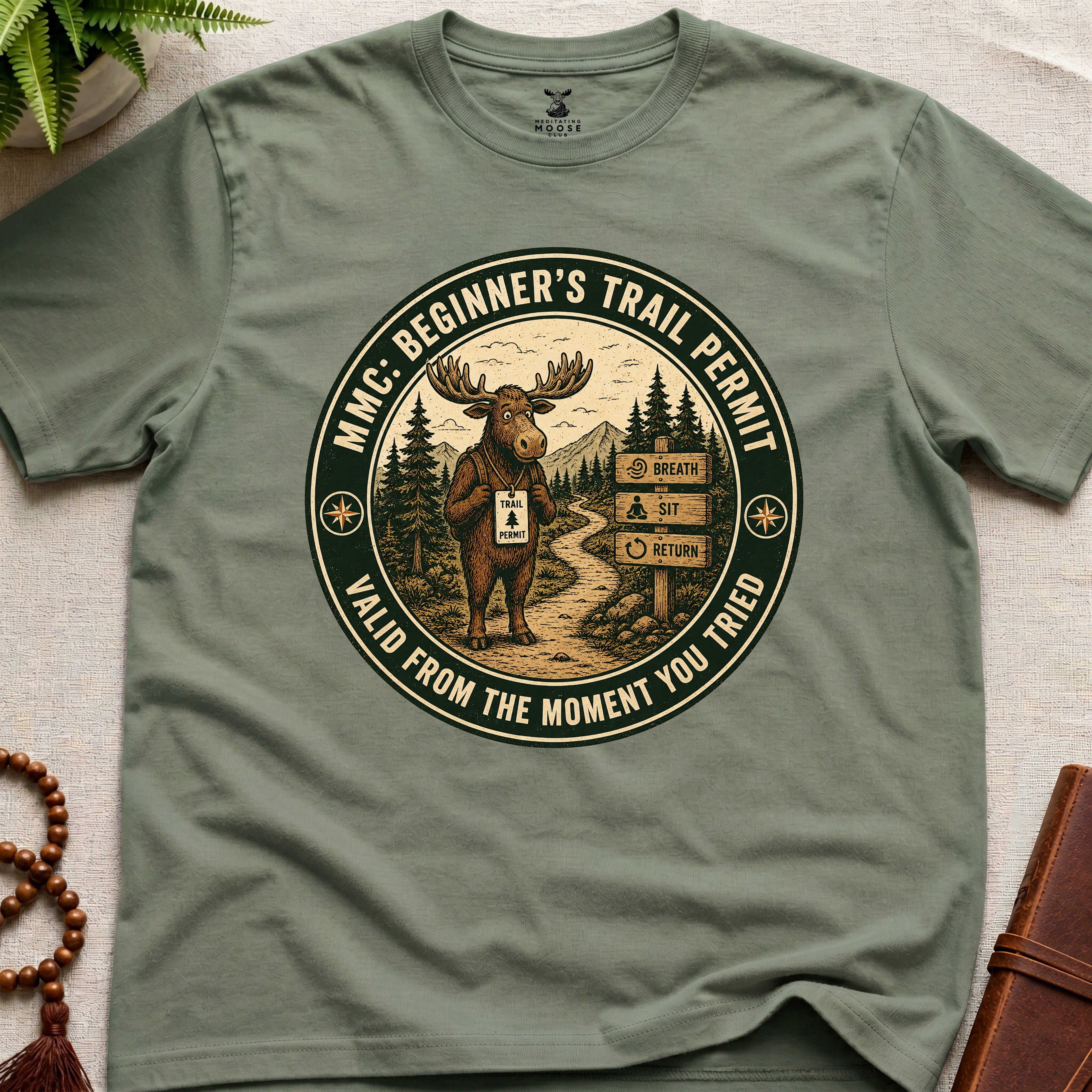 Green mindfulness t-shirt mockup featuring Beginner’s Trail Permit meditating moose beginner meditation graphic
