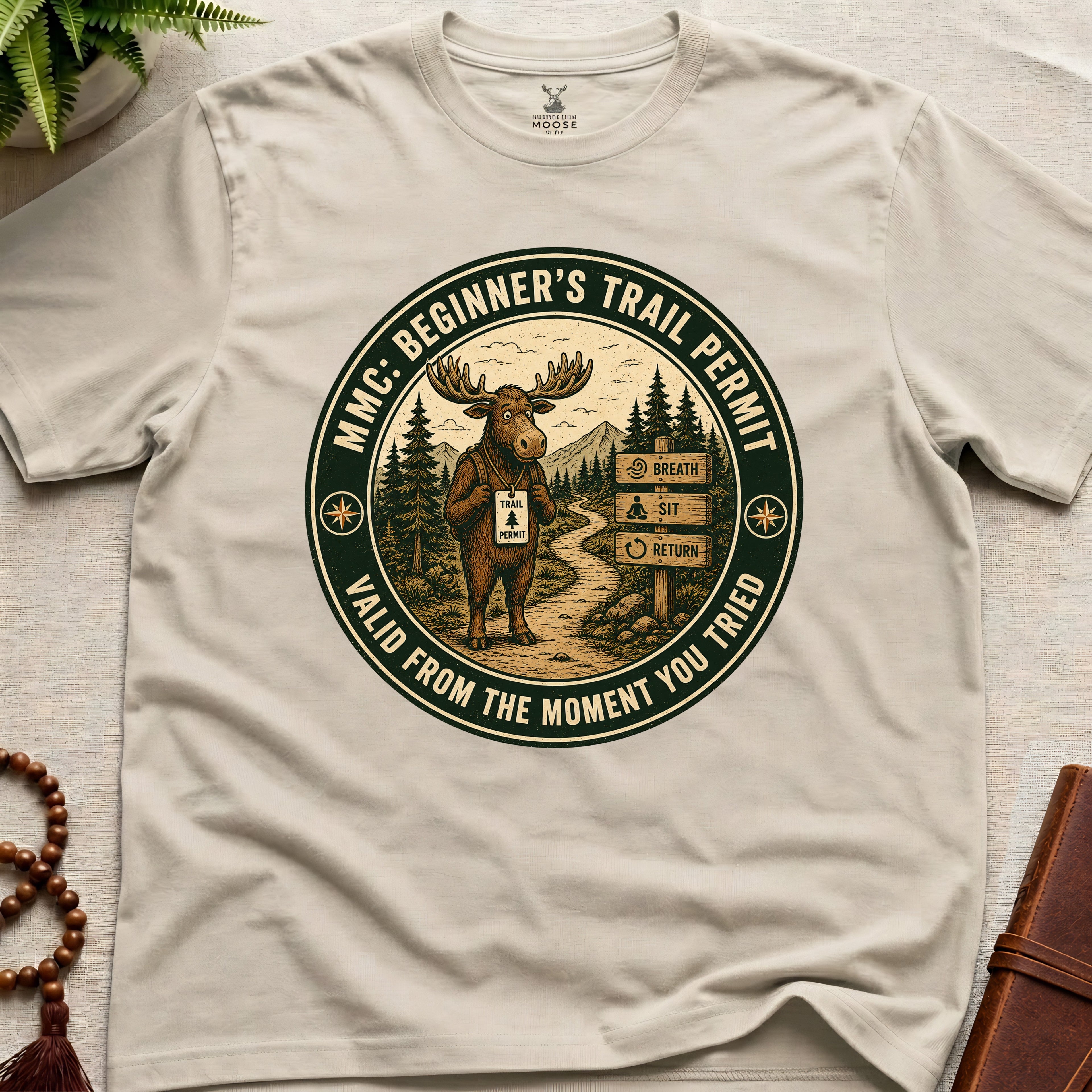 Beige mindfulness t-shirt mockup featuring Beginner’s Trail Permit meditating moose beginner meditation graphic