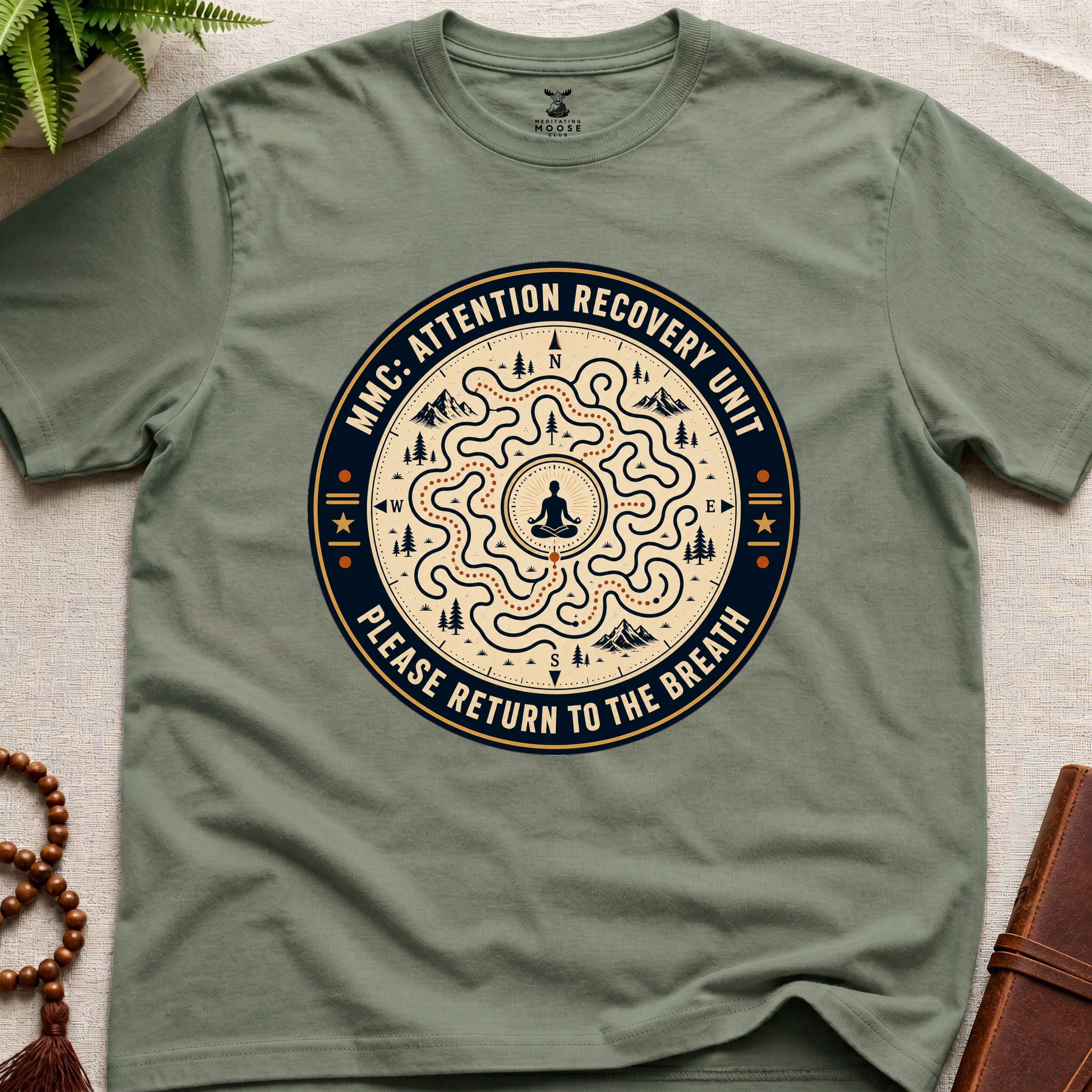 Green unisex mindfulness t-shirt mockup featuring the Meditating Moose Club Attention Recovery Unit graphic with maze navigation design and “Please Return to the Breath” text