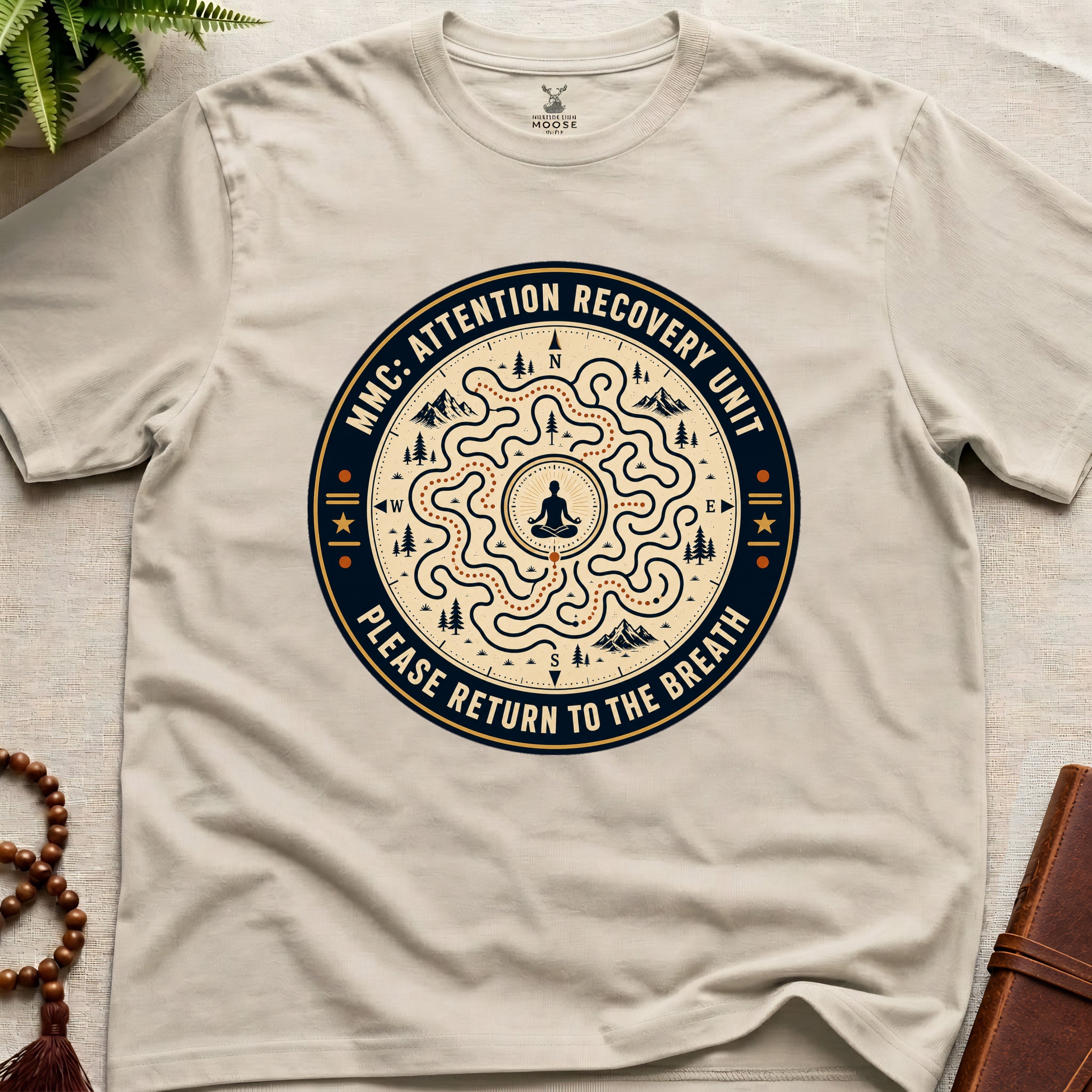 Beige unisex mindfulness t-shirt mockup featuring the Meditating Moose Club Attention Recovery Unit graphic with maze navigation design and “Please Return to the Breath” text