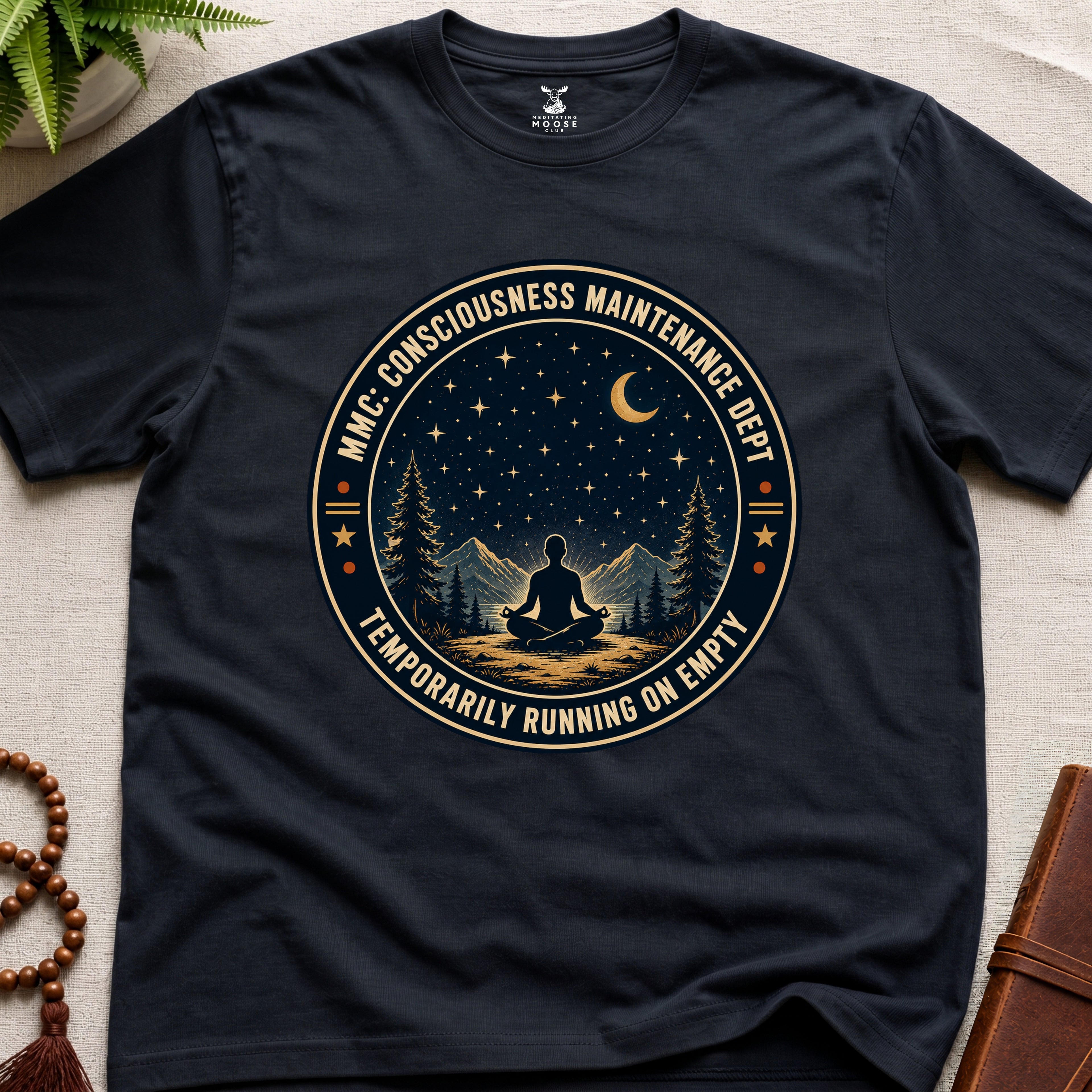 Black mindfulness t-shirt with a circular badge design featuring a meditating figure and trees - consciousness maintenance dept.