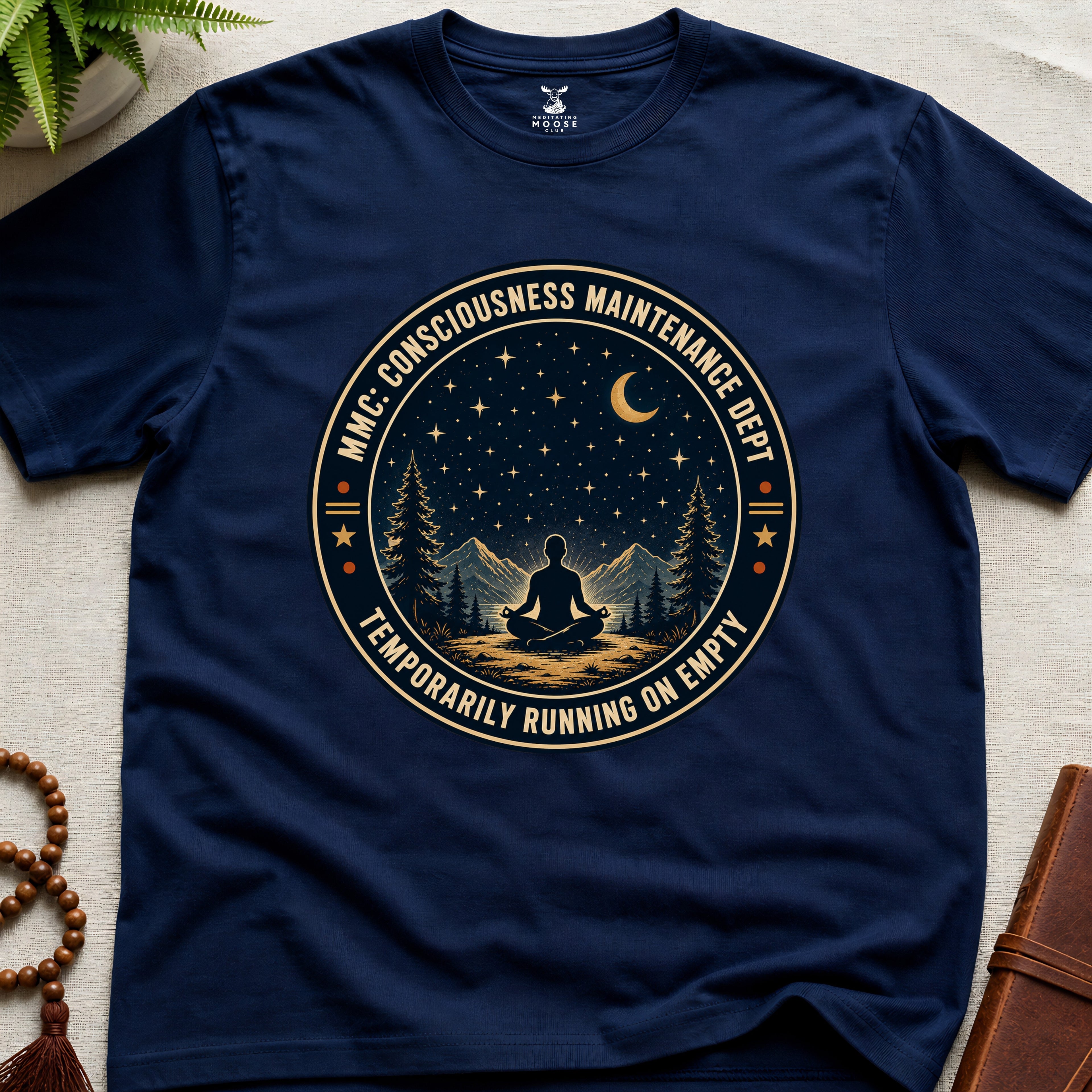 Navy blue mindfulness t-shirt with a circular badge design featuring a meditating figure and trees - consciousness maintenance dept.