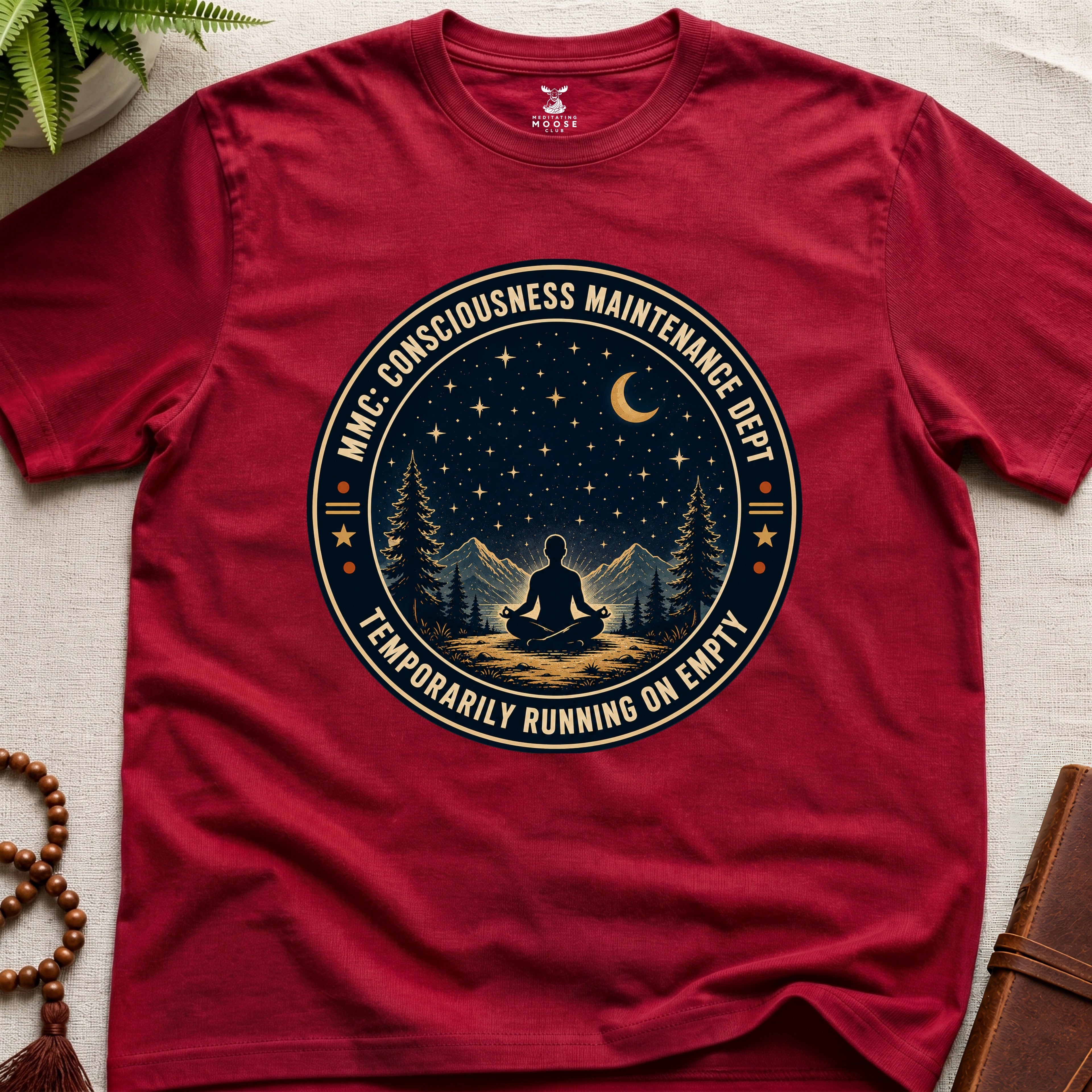 Red mindfulness t-shirt with a circular badge design featuring a meditating figure and trees - consciousness maintenance dept.