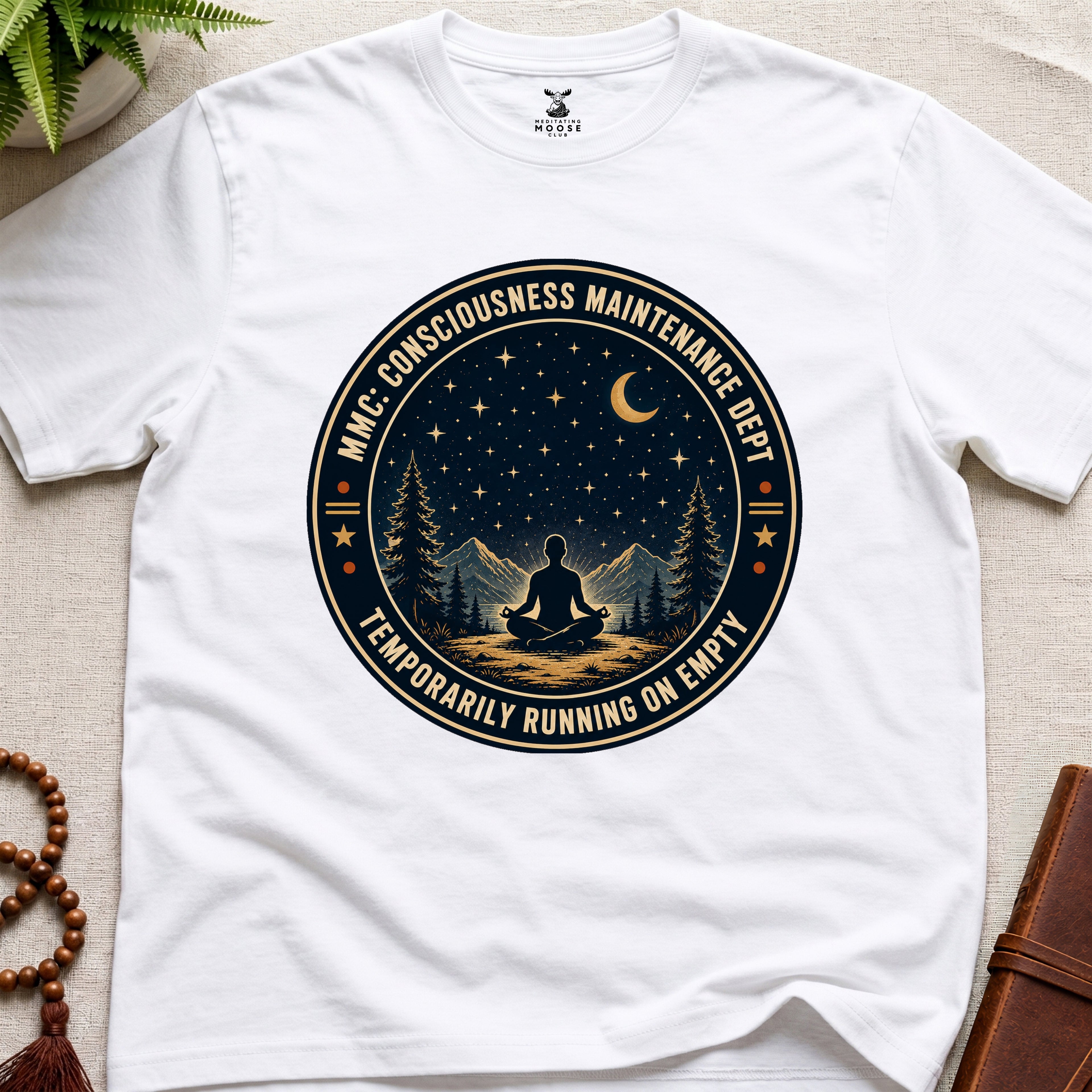 White mindfulness t-shirt with a circular badge design featuring a meditating figure and trees - consciousness maintenance dept.