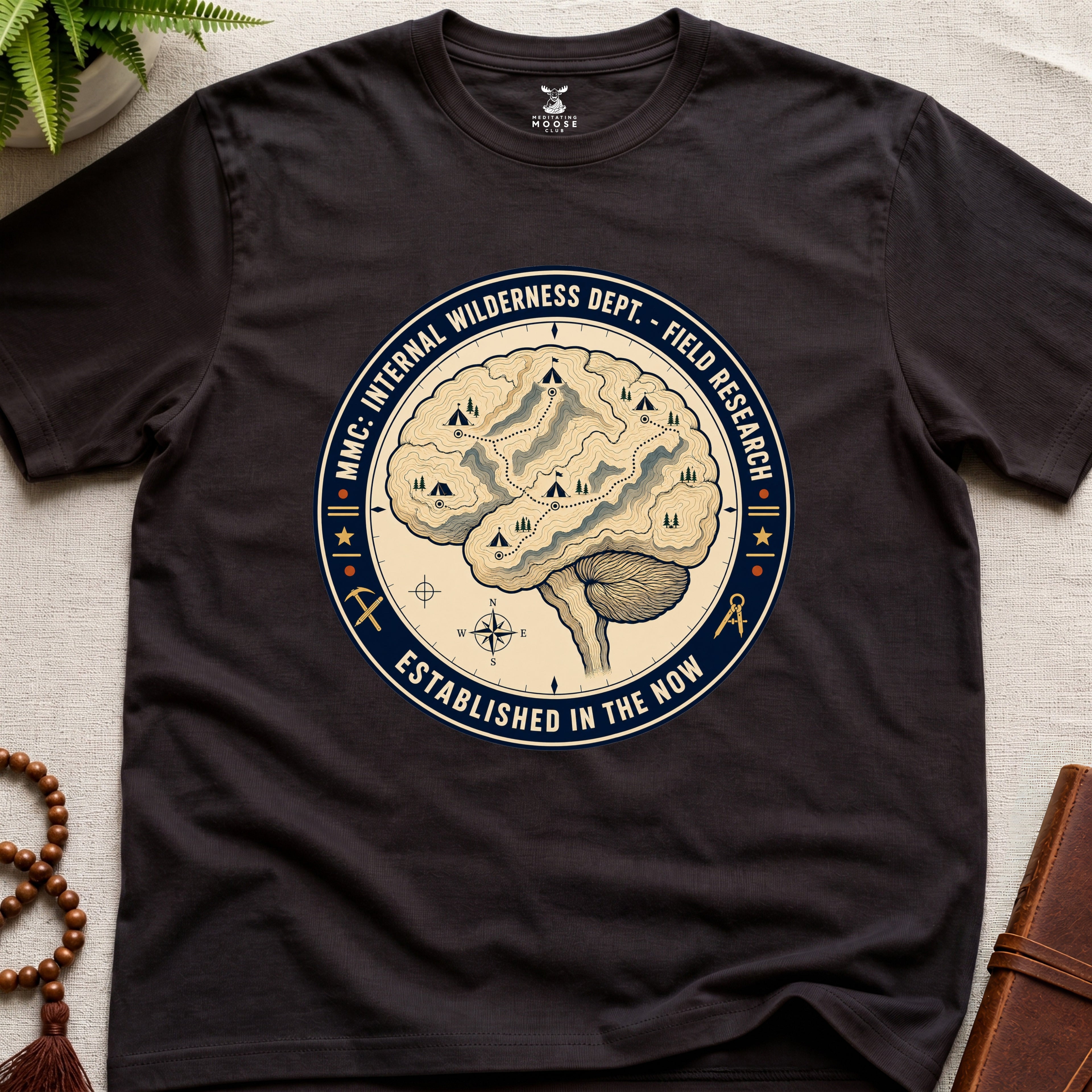 Dark brown mindfulness t-shirt with a brain graphic and text on a light surface.