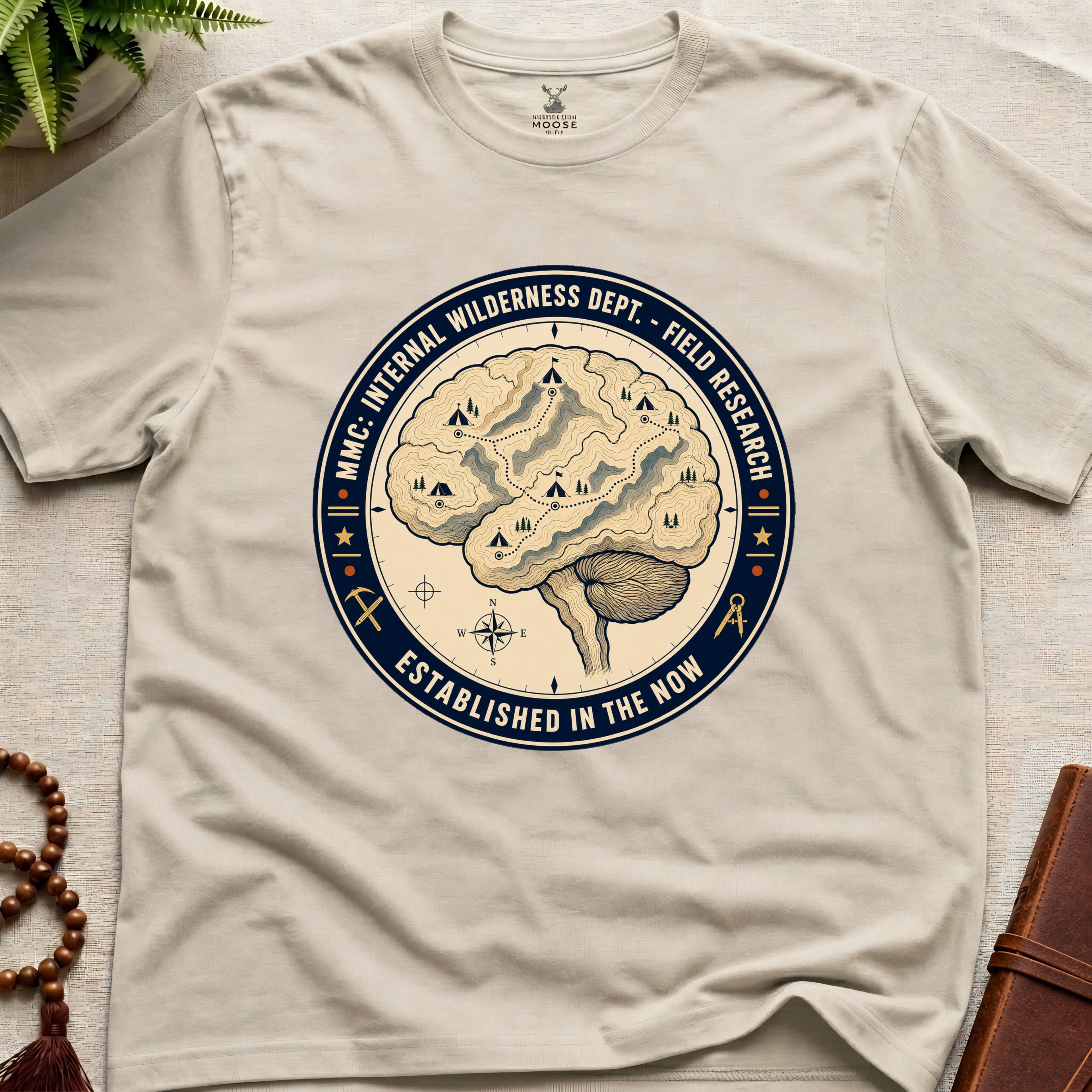 Beige mindfulness t-shirt with a brain graphic and text on a light surface.