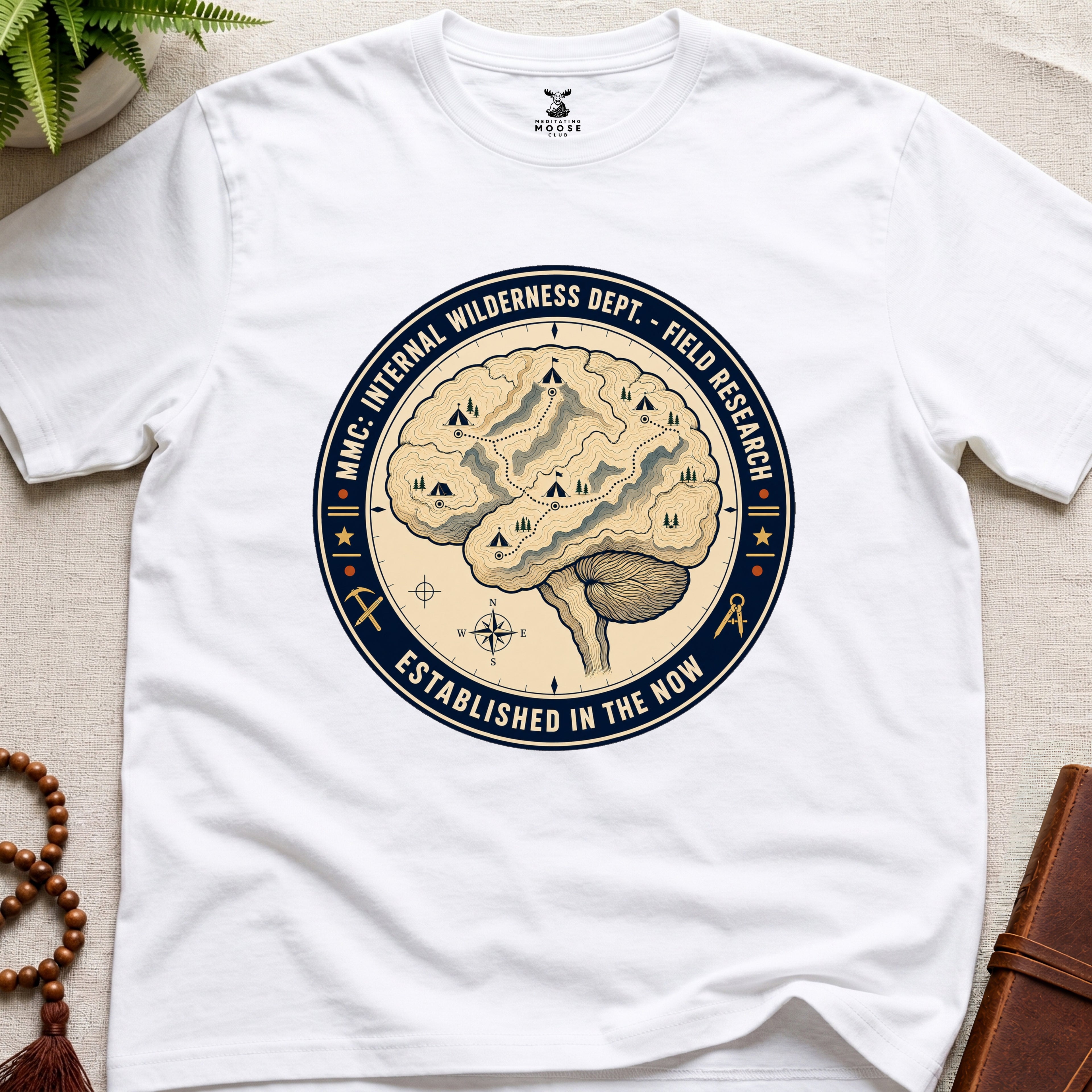 White mindfulness t-shirt with a brain graphic and text on a light surface.