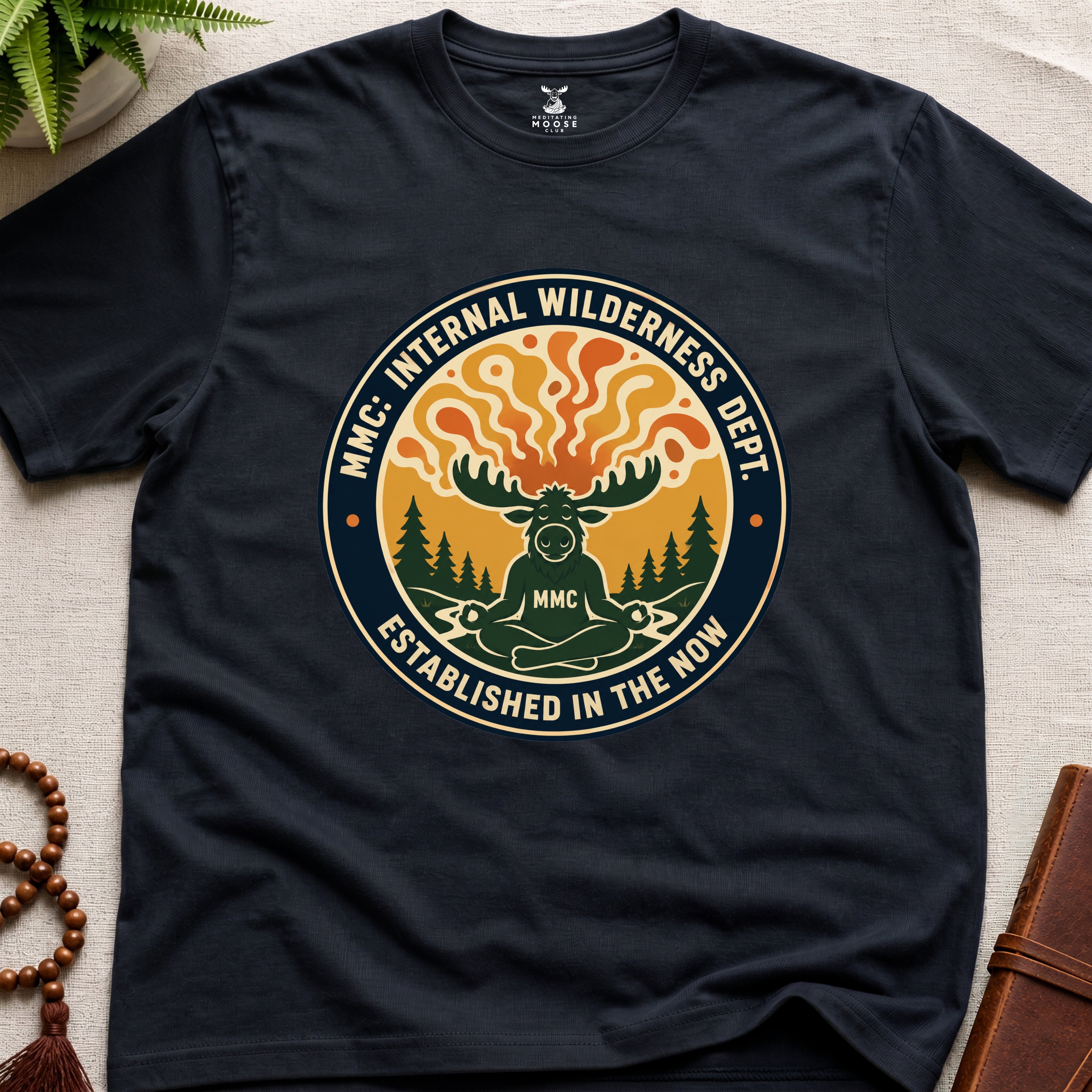 Black t-shirt with a graphic design featuring a moose and trees on a light beige surface.