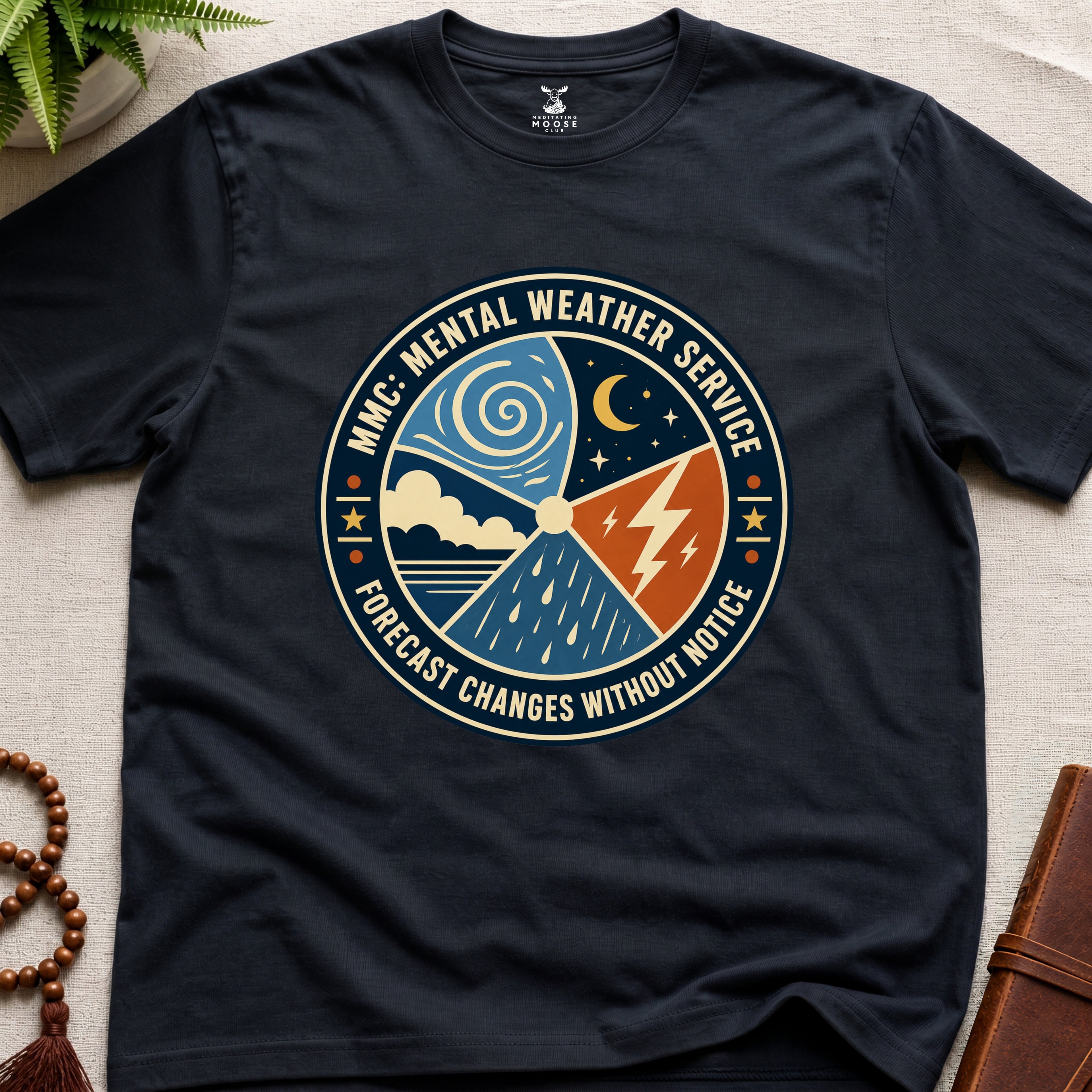 Black t-shirt with a circular graphic design mental weather service on a light surface.