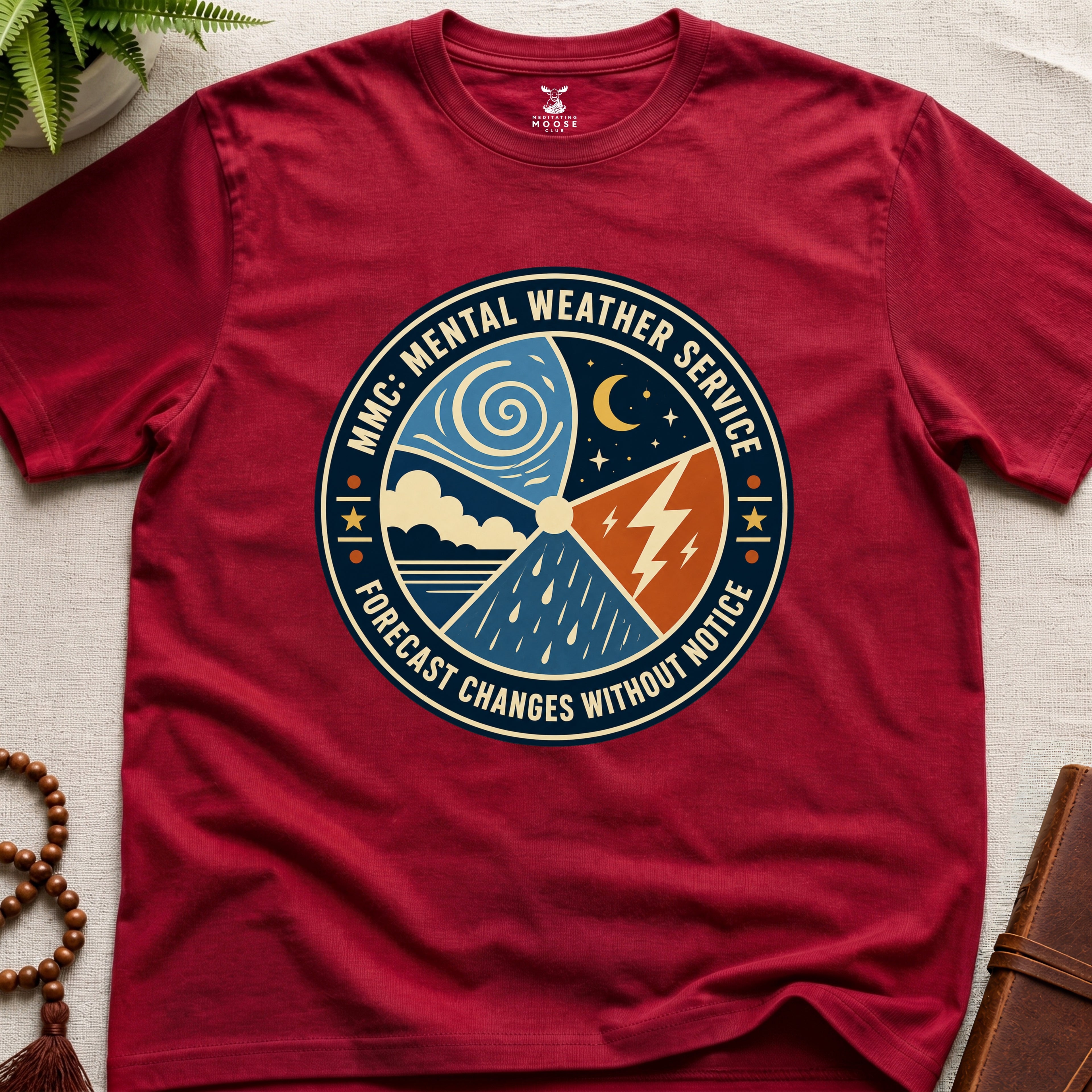 Red t-shirt with a circular graphic design mental weather service on a light surface.