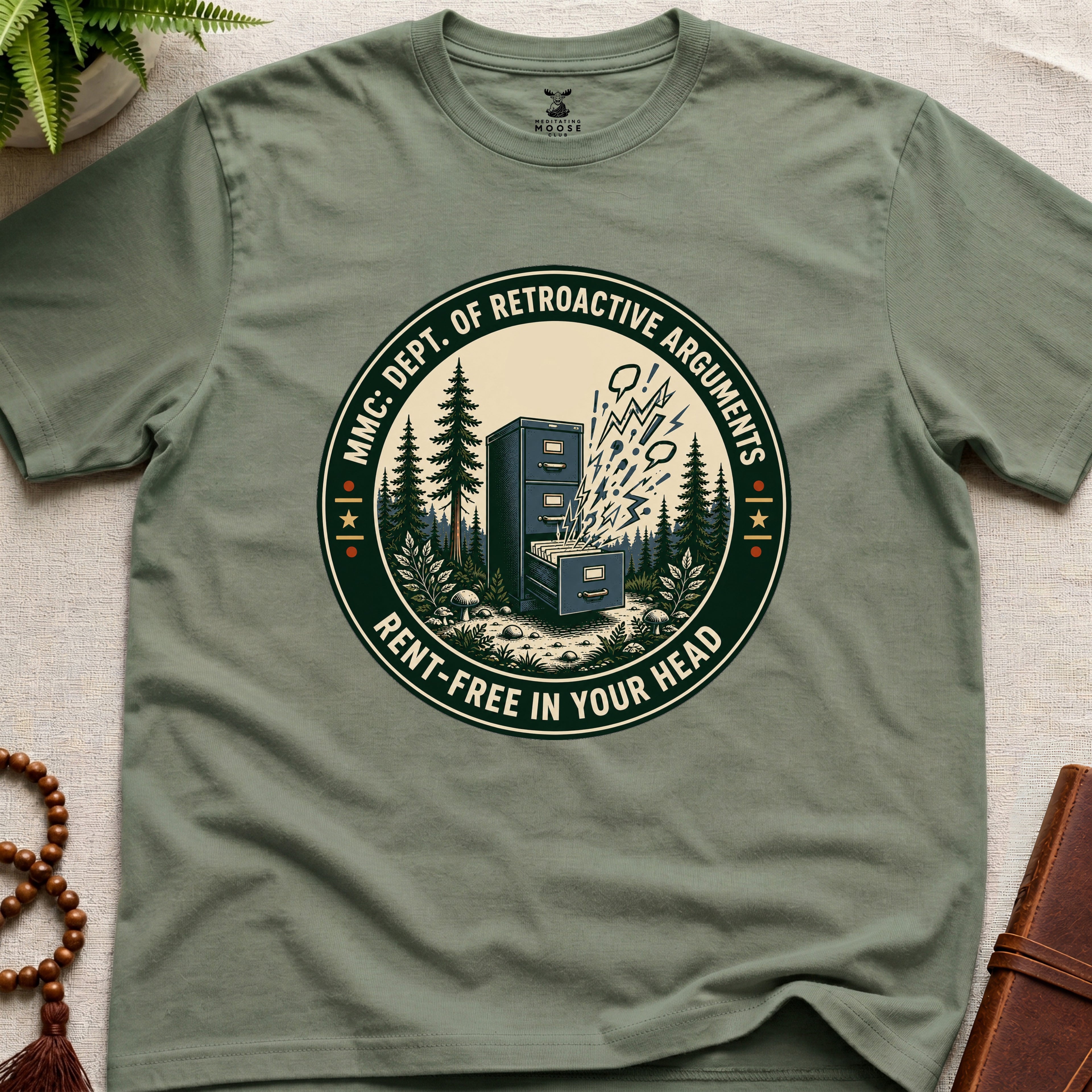 Military Green t-shirt with a badge graphic design "Dept. of retroactive arguments" on a light surface.