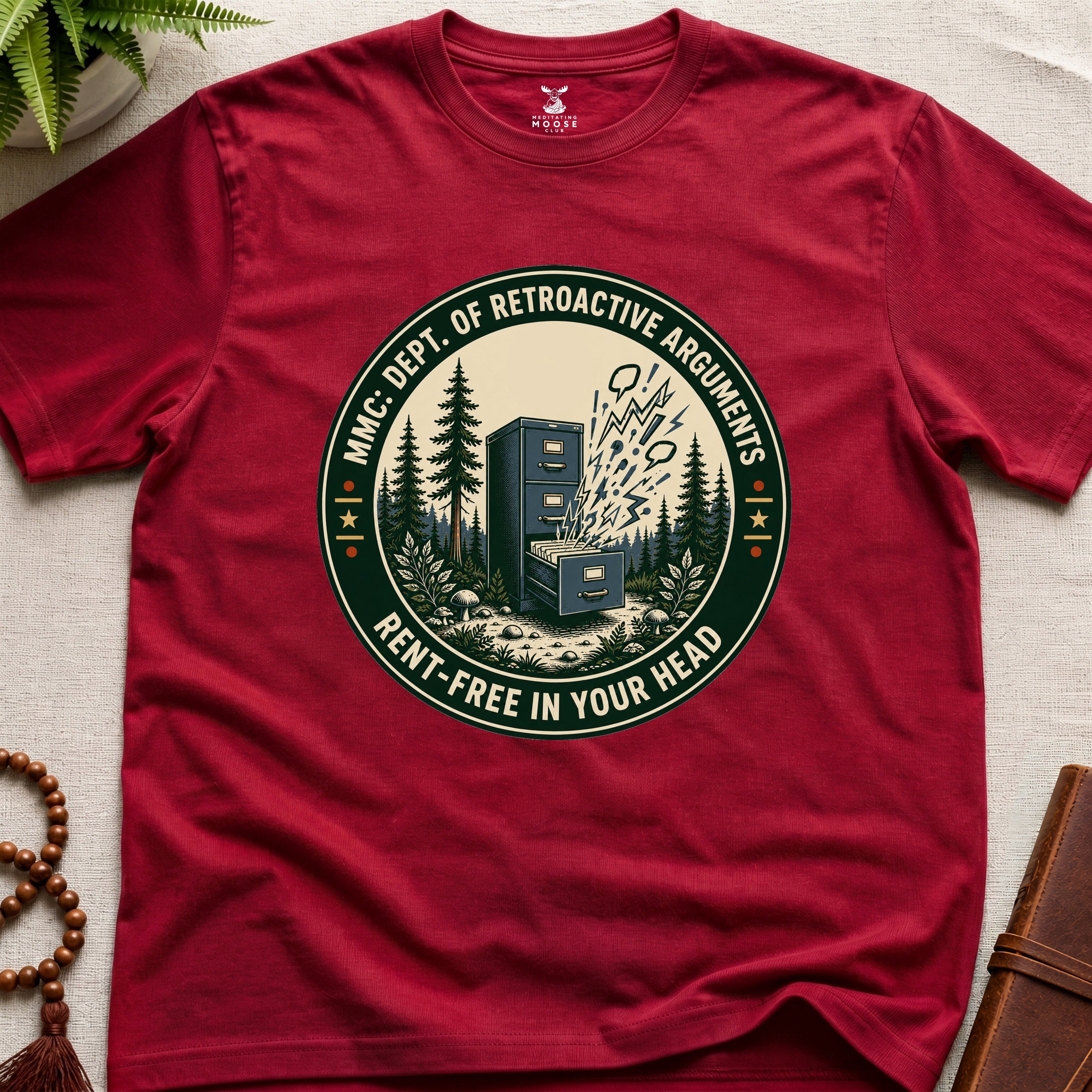 Red t-shirt with a badge graphic design "Dept. of retroactive arguments" on a light surface.