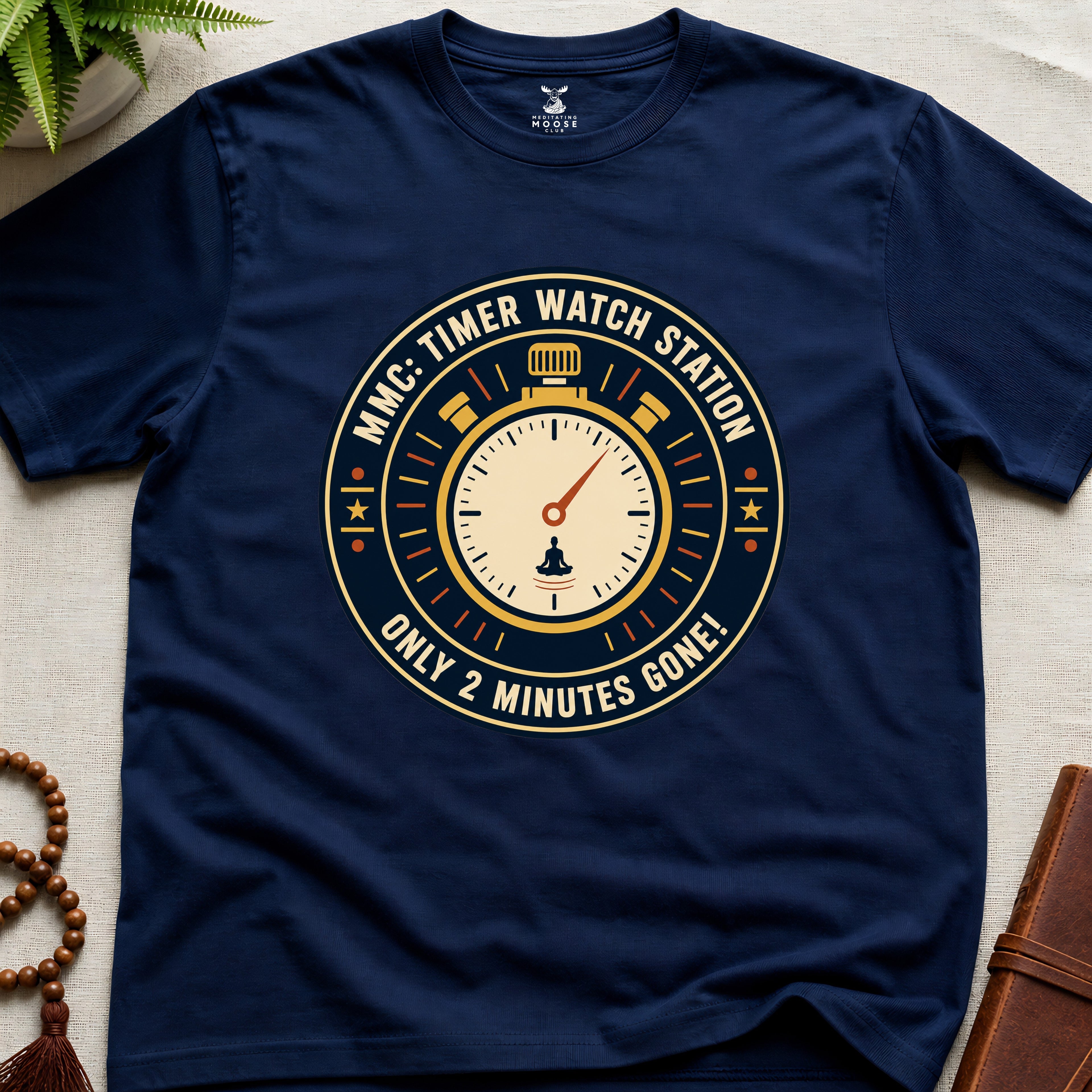 Navy t-shirt with a clock graphic and text "only 2 minutes gone!" on a beige surface.
