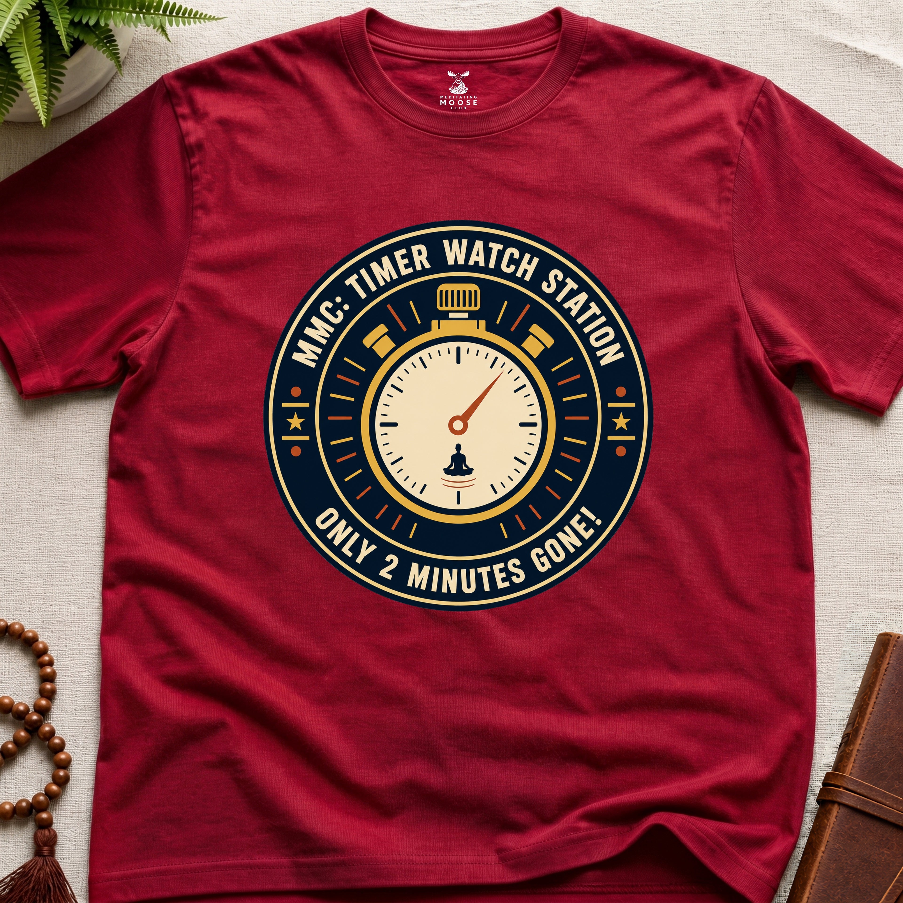 Red t-shirt with a clock graphic and text "only 2 minutes gone!" on a beige surface.