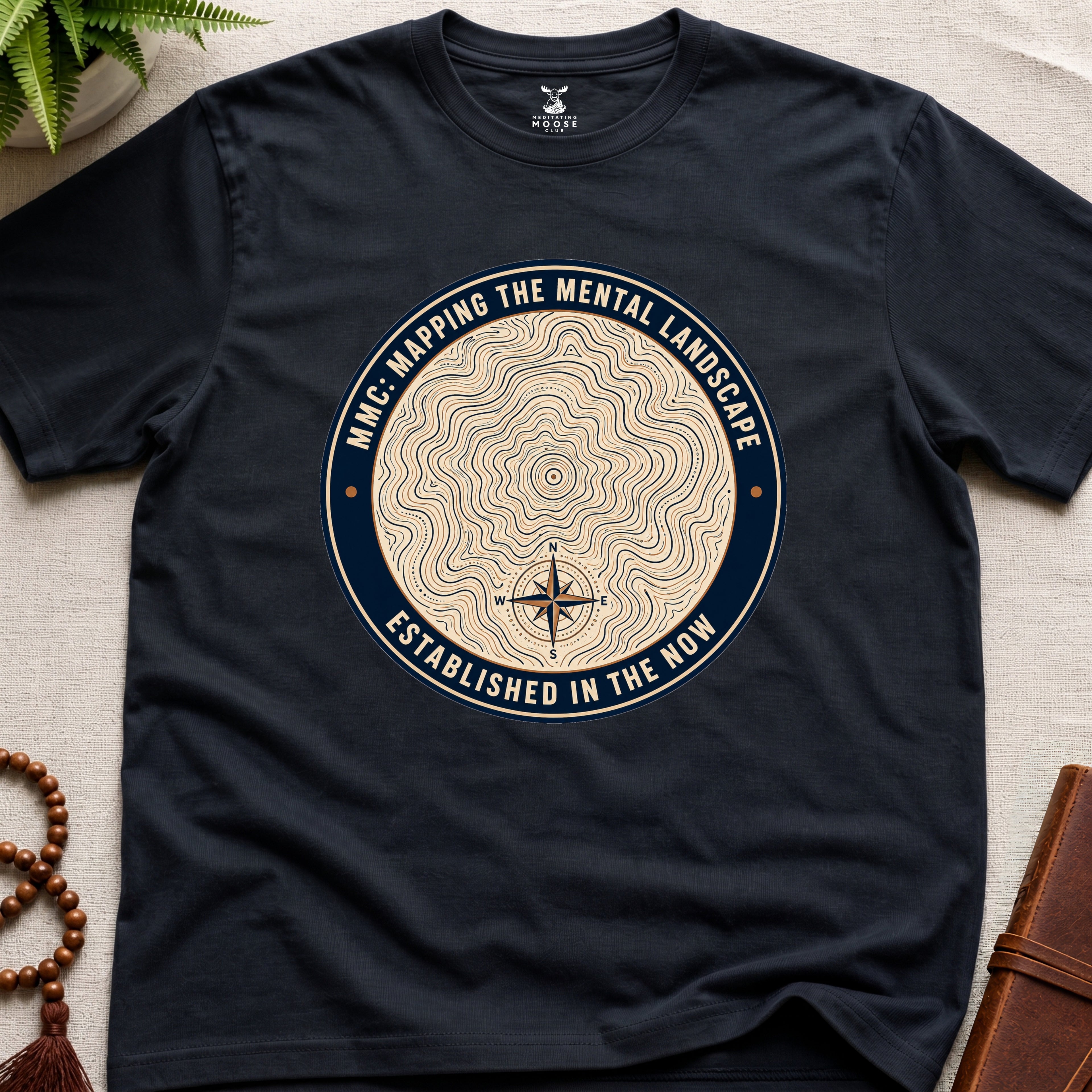 Black mindfulness t-shirt with topographic landscape badge design featuring compass