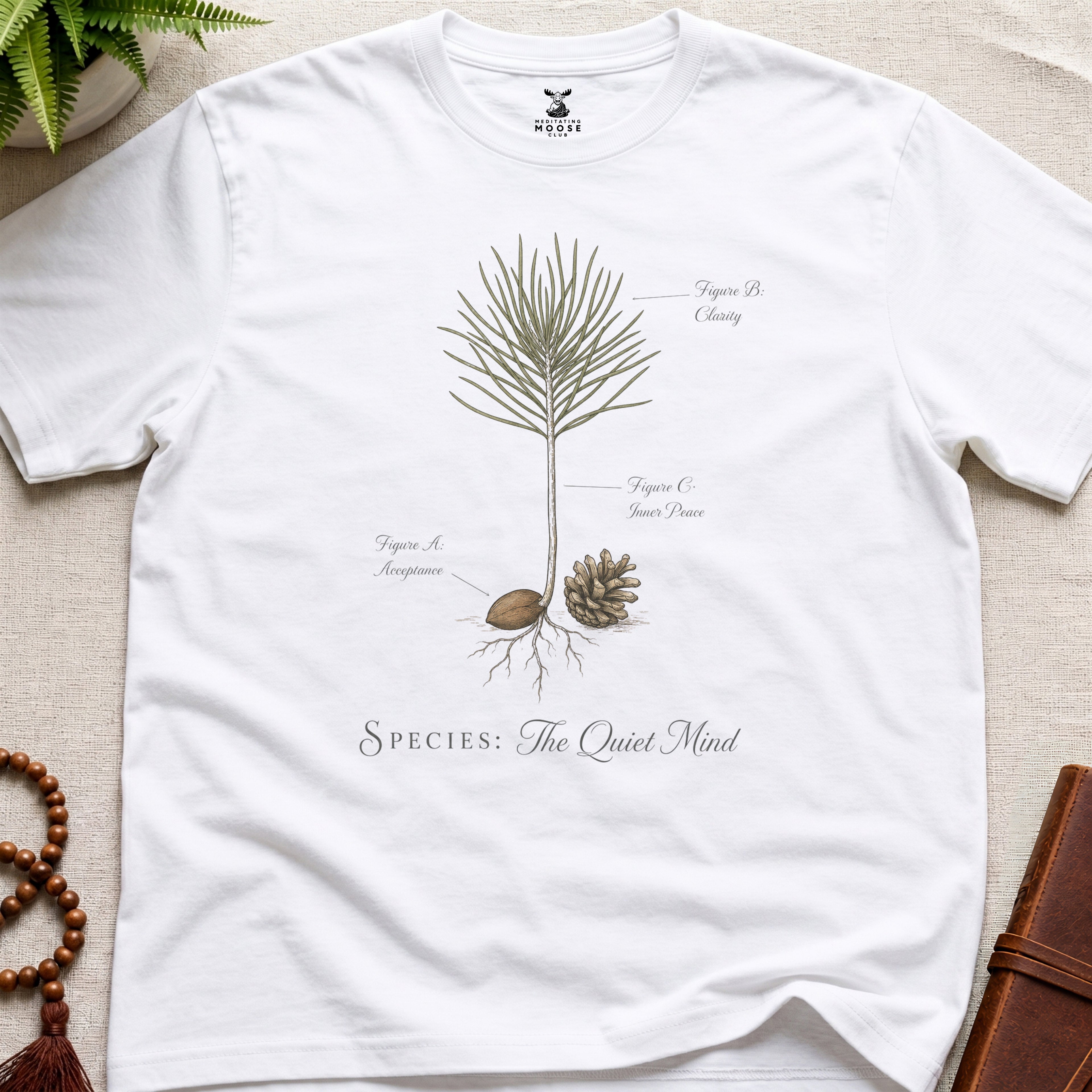 White t-shirt with botanical design and text on a beige surface