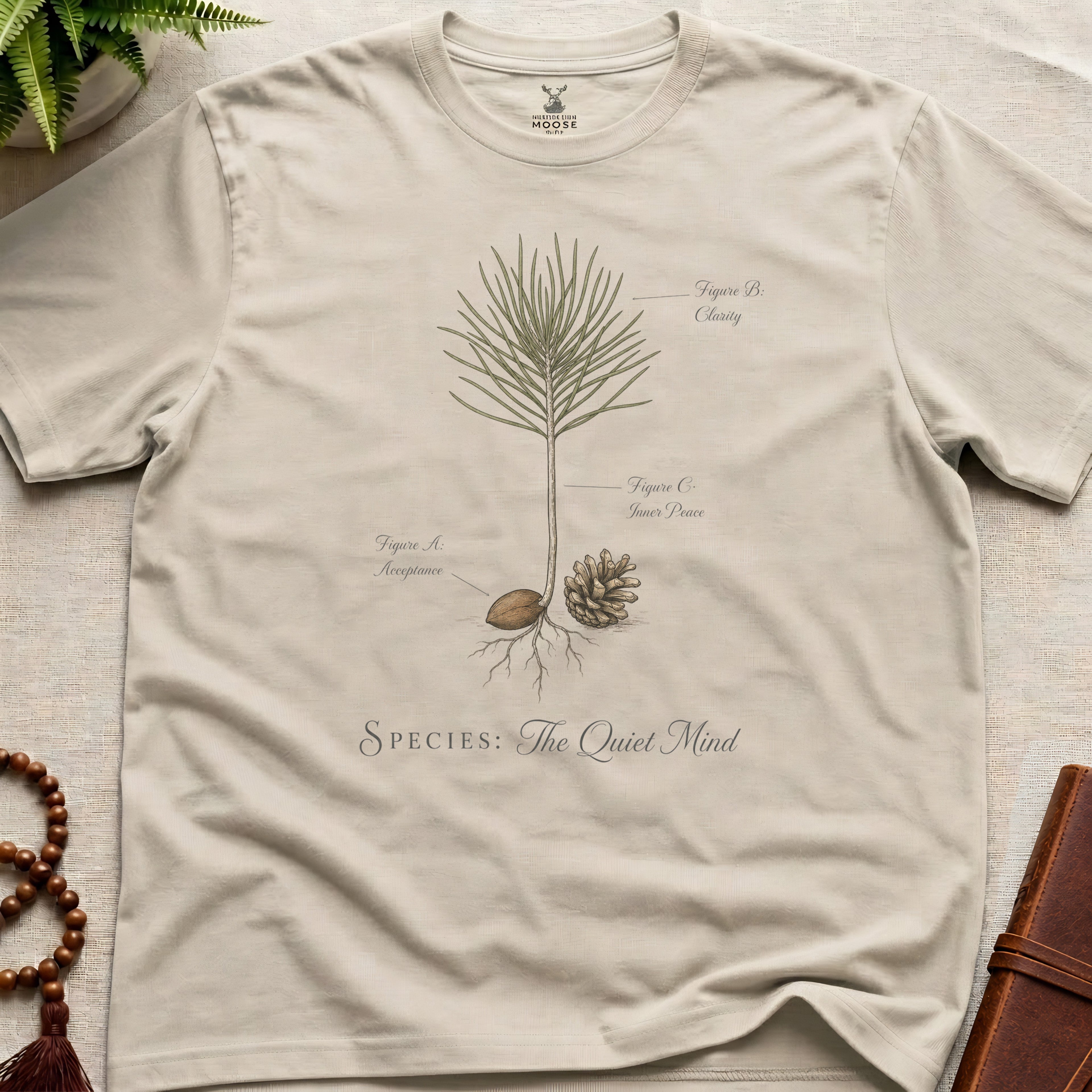 Beige t-shirt with nature-themed design and text on a light surface.