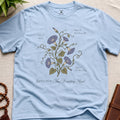 Light blue t-shirt with floral design and text on a beige surface