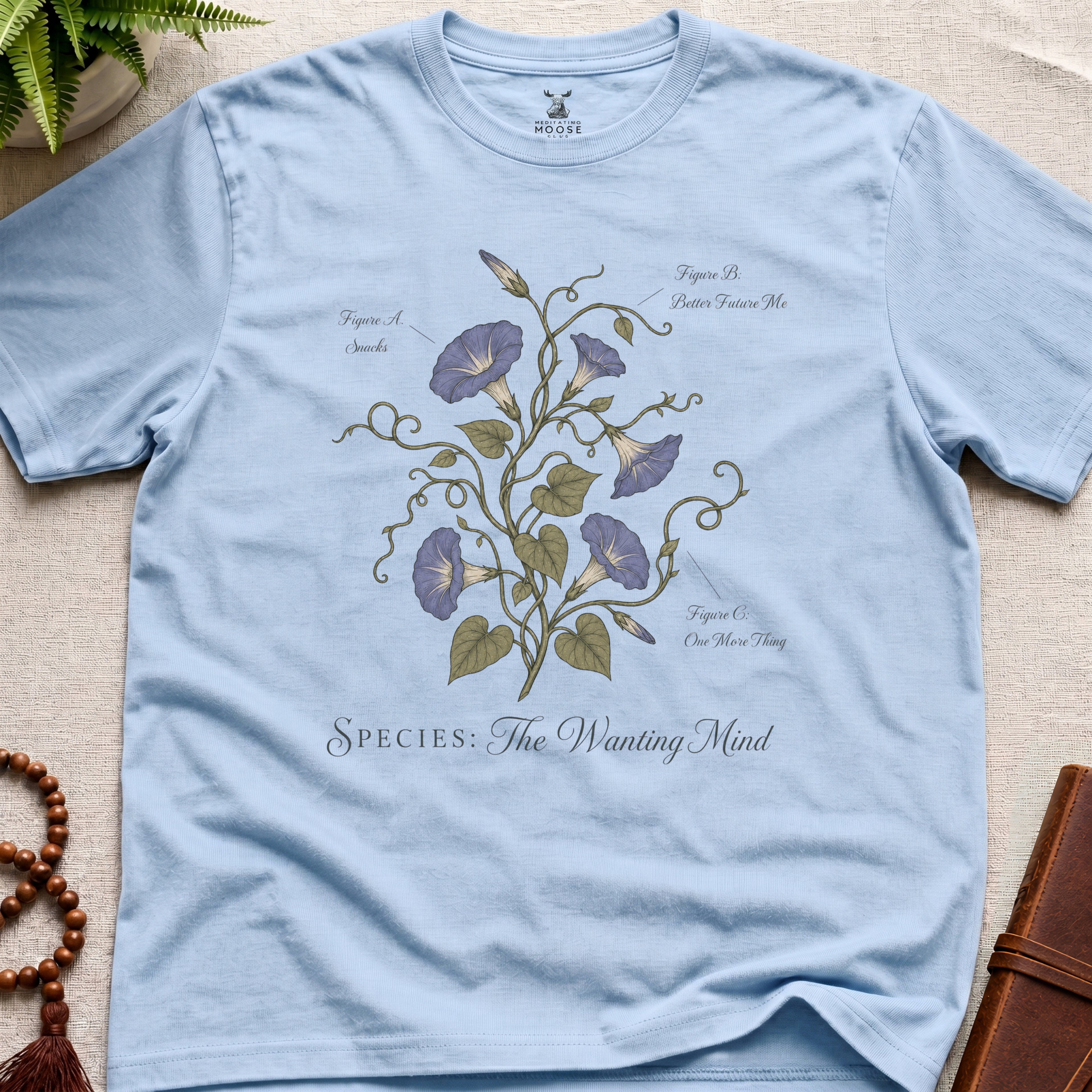 Light blue t-shirt with floral design and text on a beige surface