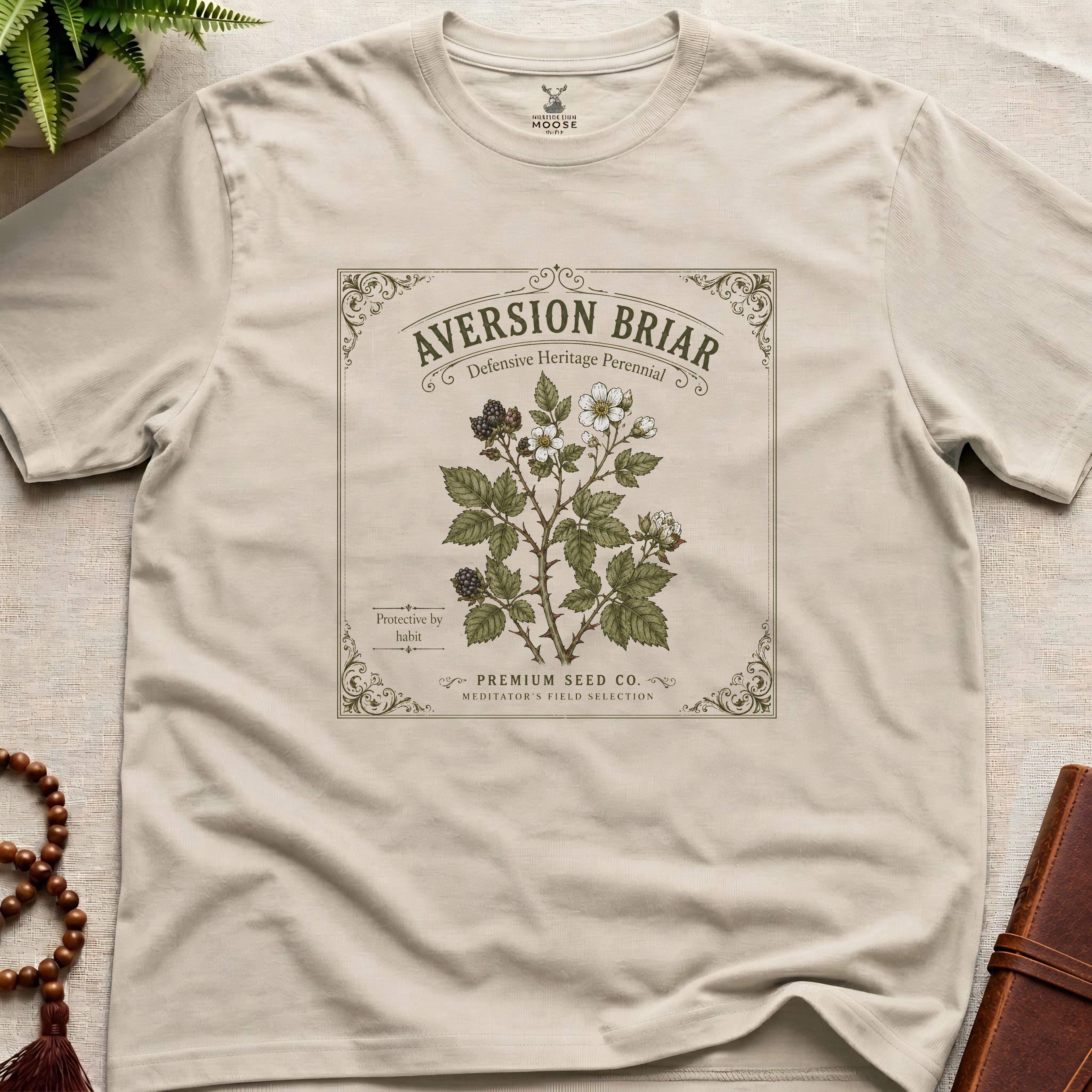 Beige t-shirt with vintage-style plant label design on a light surface.