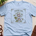 Light blue t-shirt with a vintage-style seed packet design featuring a purple vine flower craving vine, sensual climbing variey