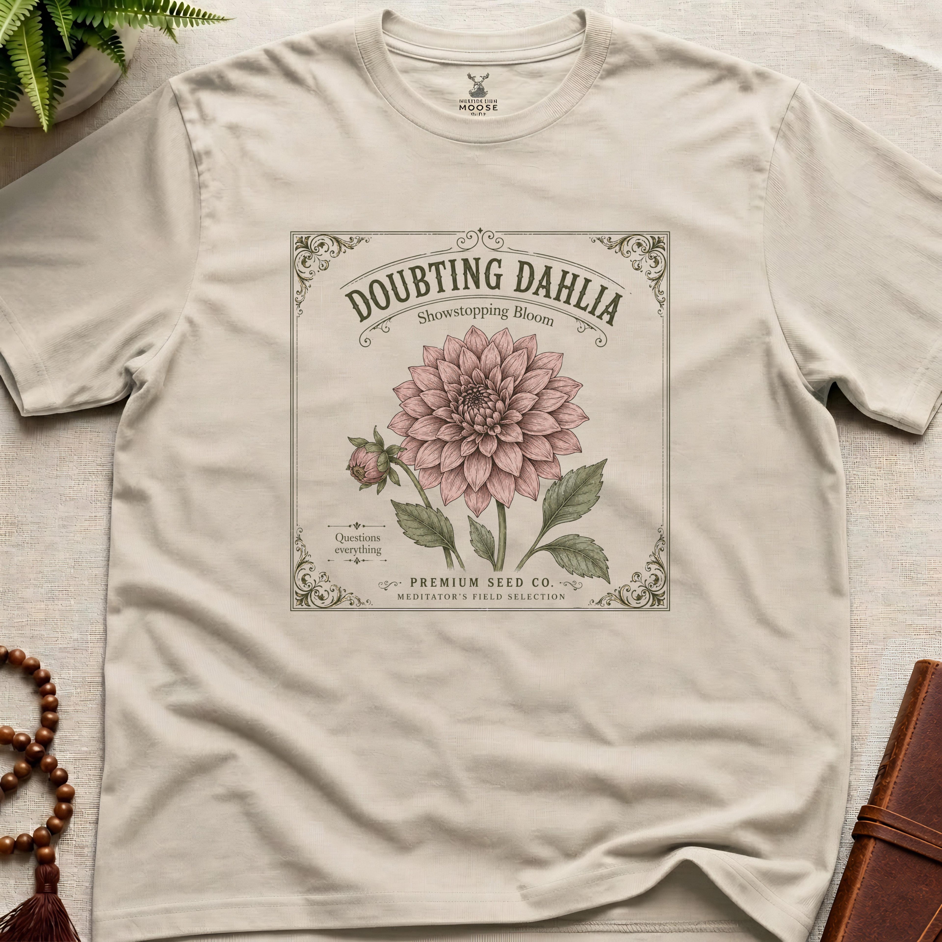 Beige t-shirt with a vintage seed packet style flower graphic doubting dahlia showstopping bloom