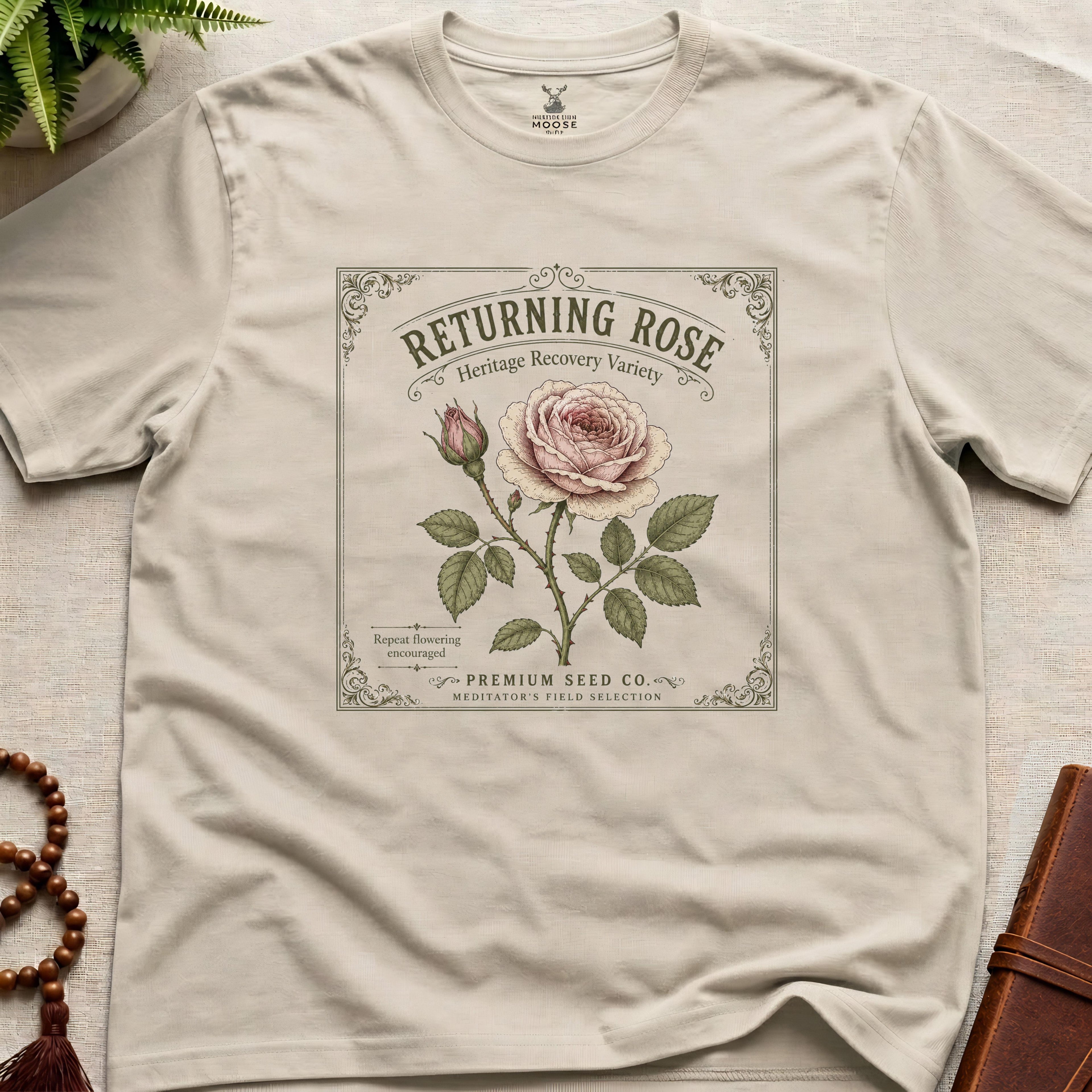 Beige t-shirt with vintage see packet style, returning rose design on a beige surface.