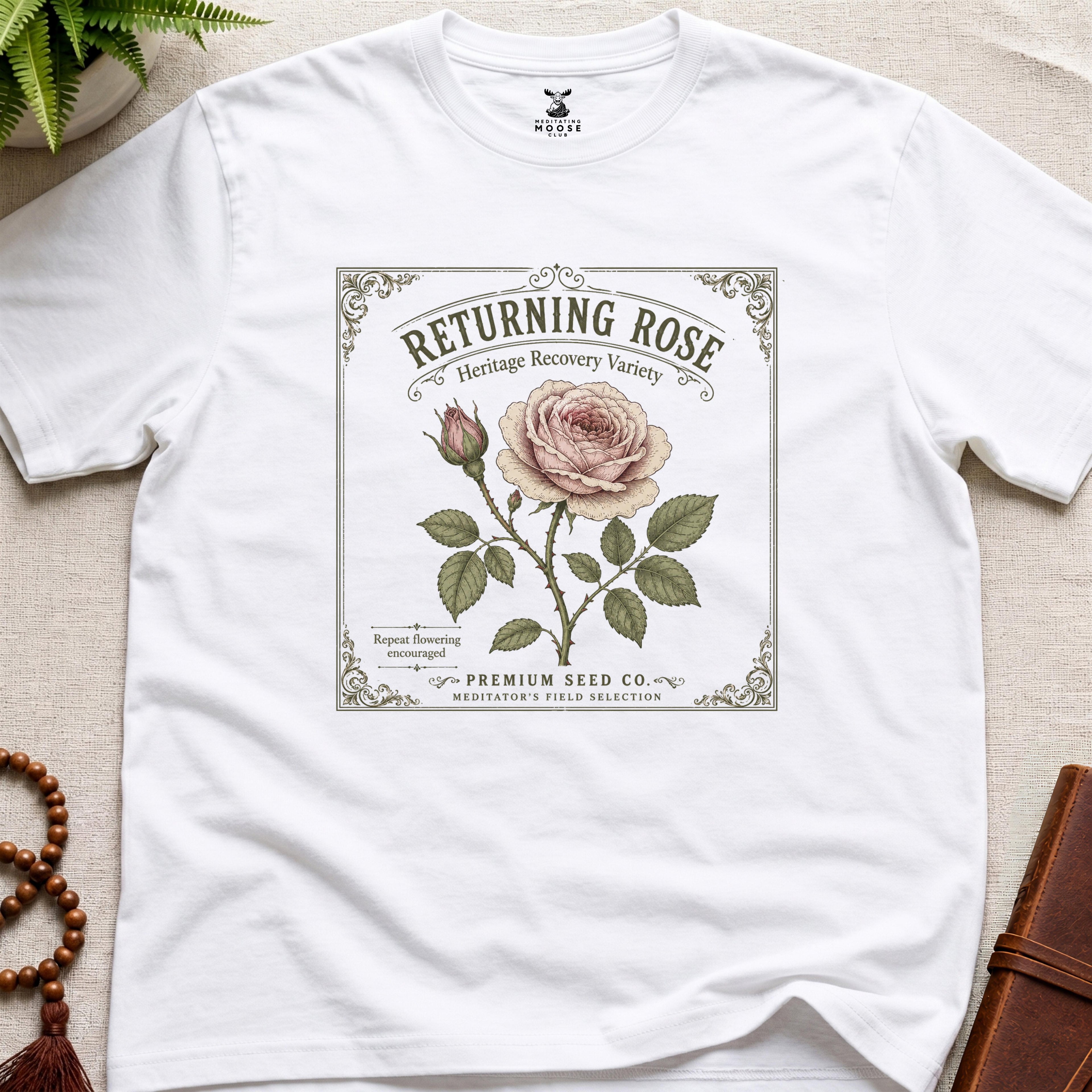 White t-shirt with vintage see packet style, returning rose design on a beige surface.