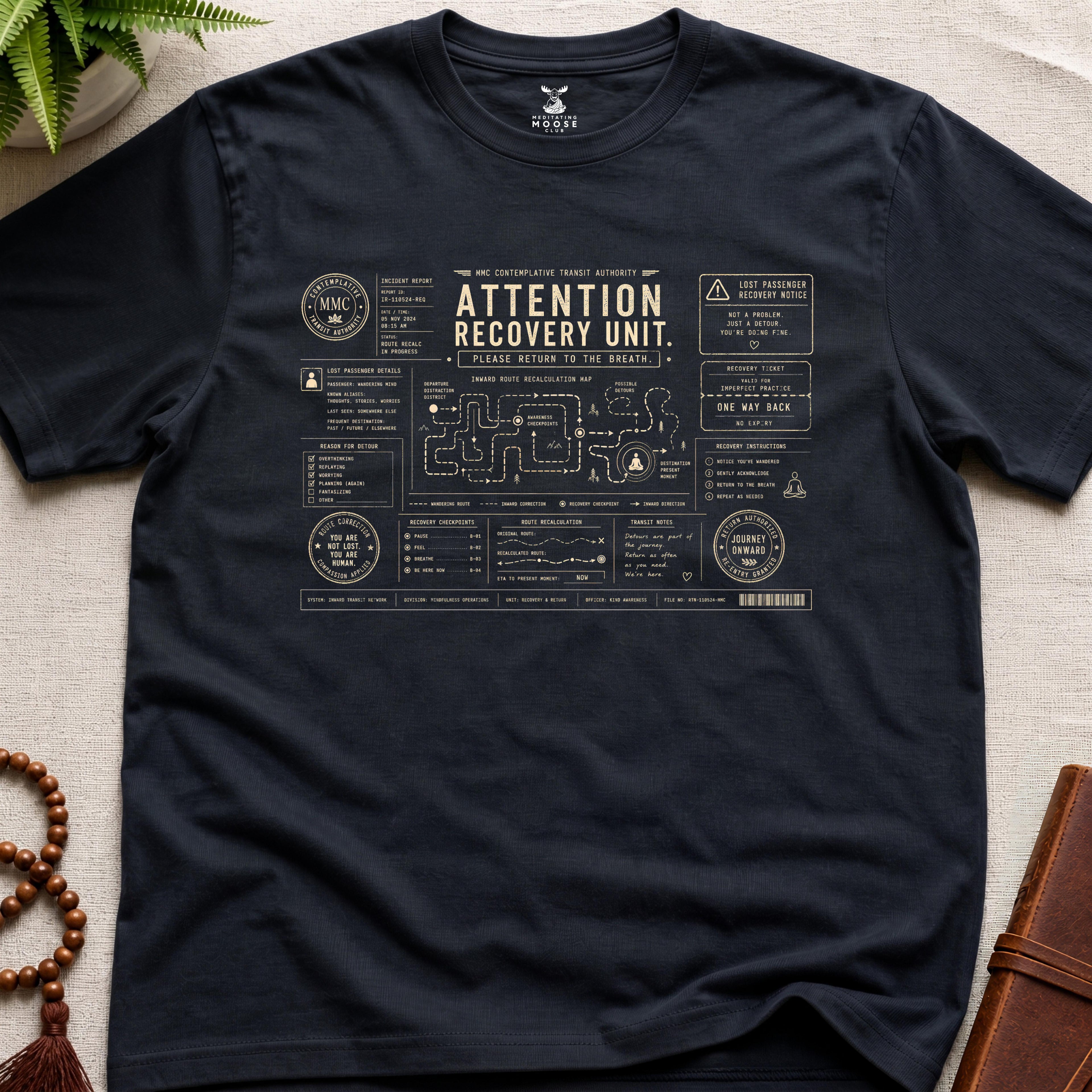 Black mindfulness transit recovery t-shirt graphic reading “Attention Recovery Unit” with inward rerouting diagrams and contemplative navigation systems.