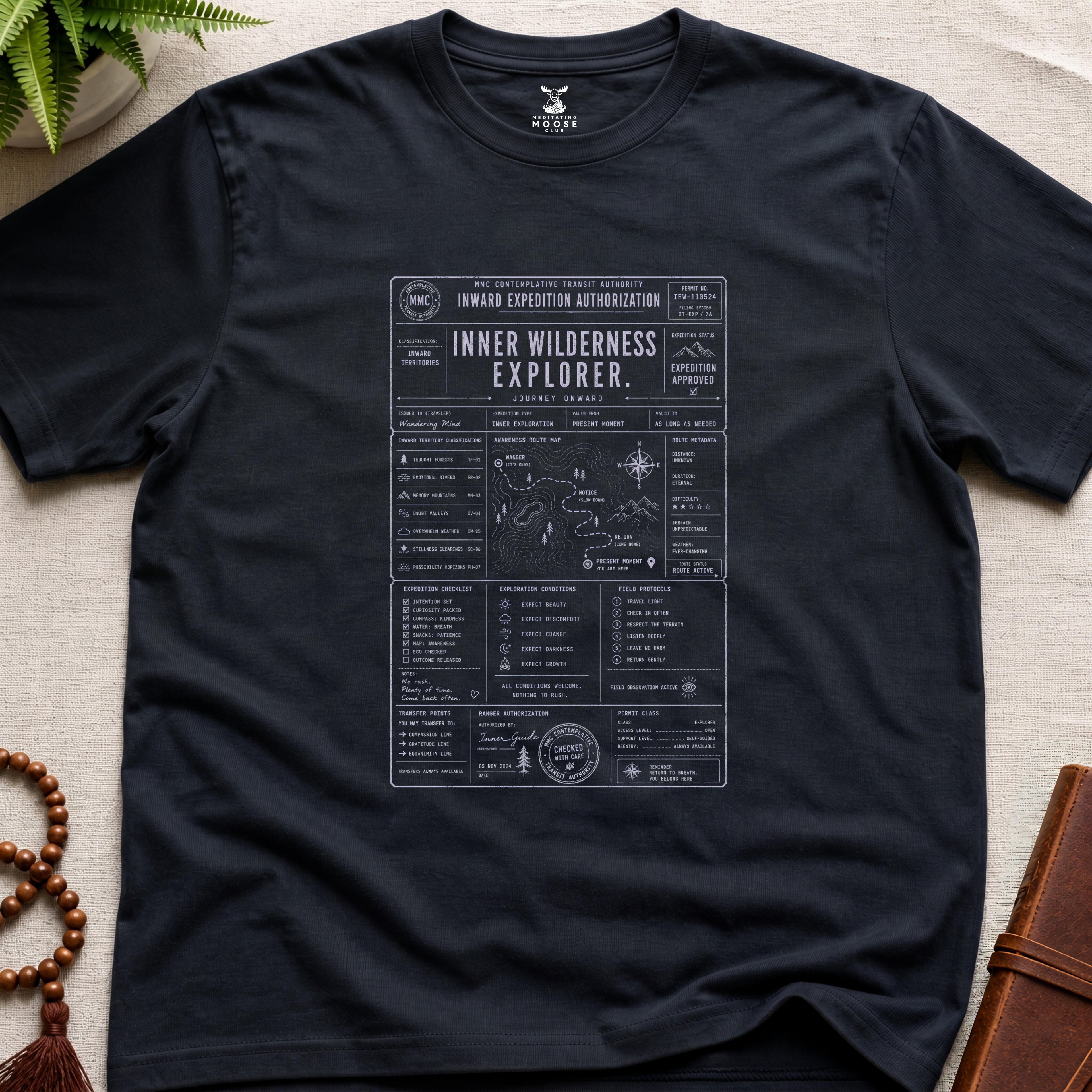 Black contemplative inward expedition permit t-shirt graphic reading “Inner Wilderness Explorer” with navigation charts and mindfulness field systems.