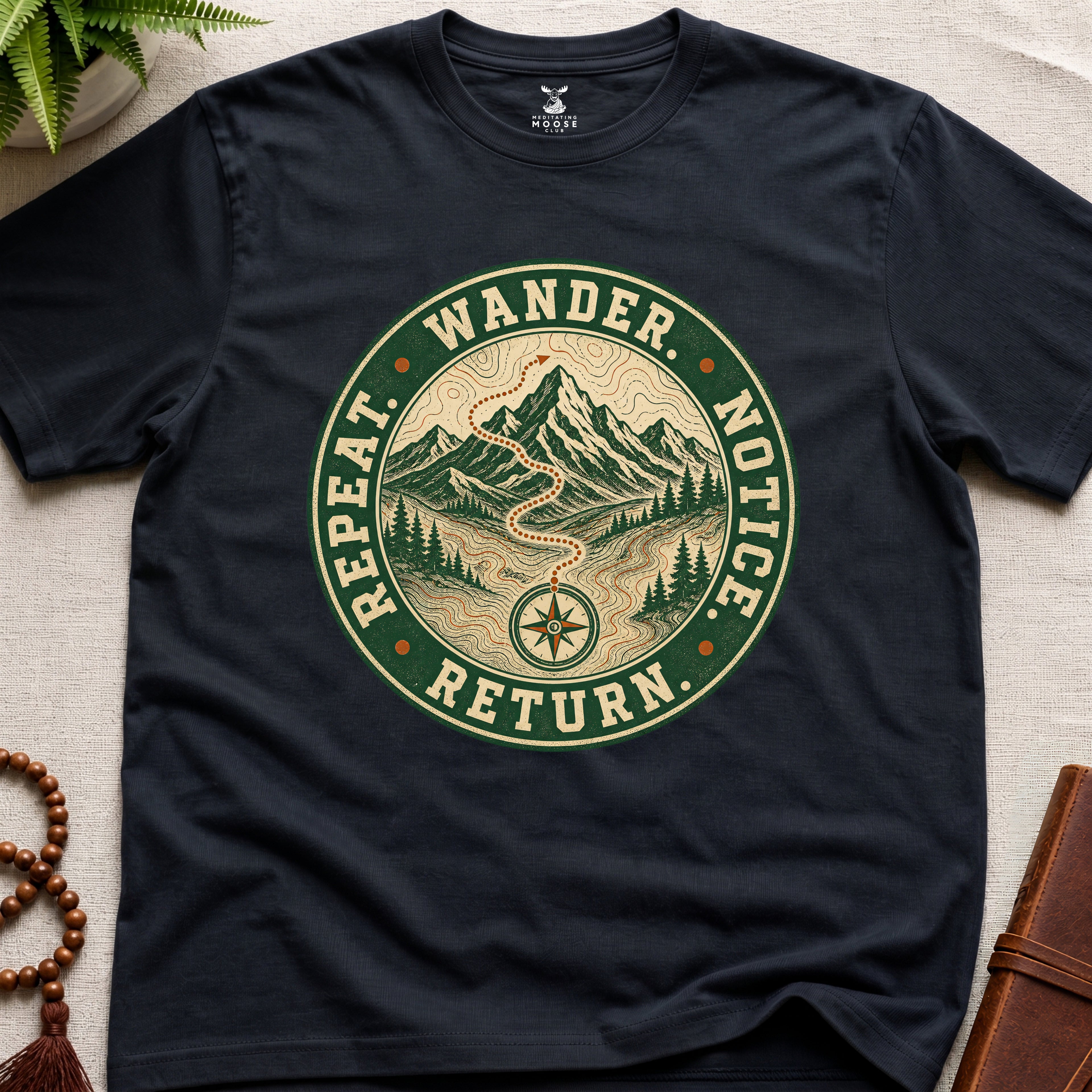 Black mindfulness t-shirt mockup featuring Wander Notice Return vintage mountain meditation badge graphic