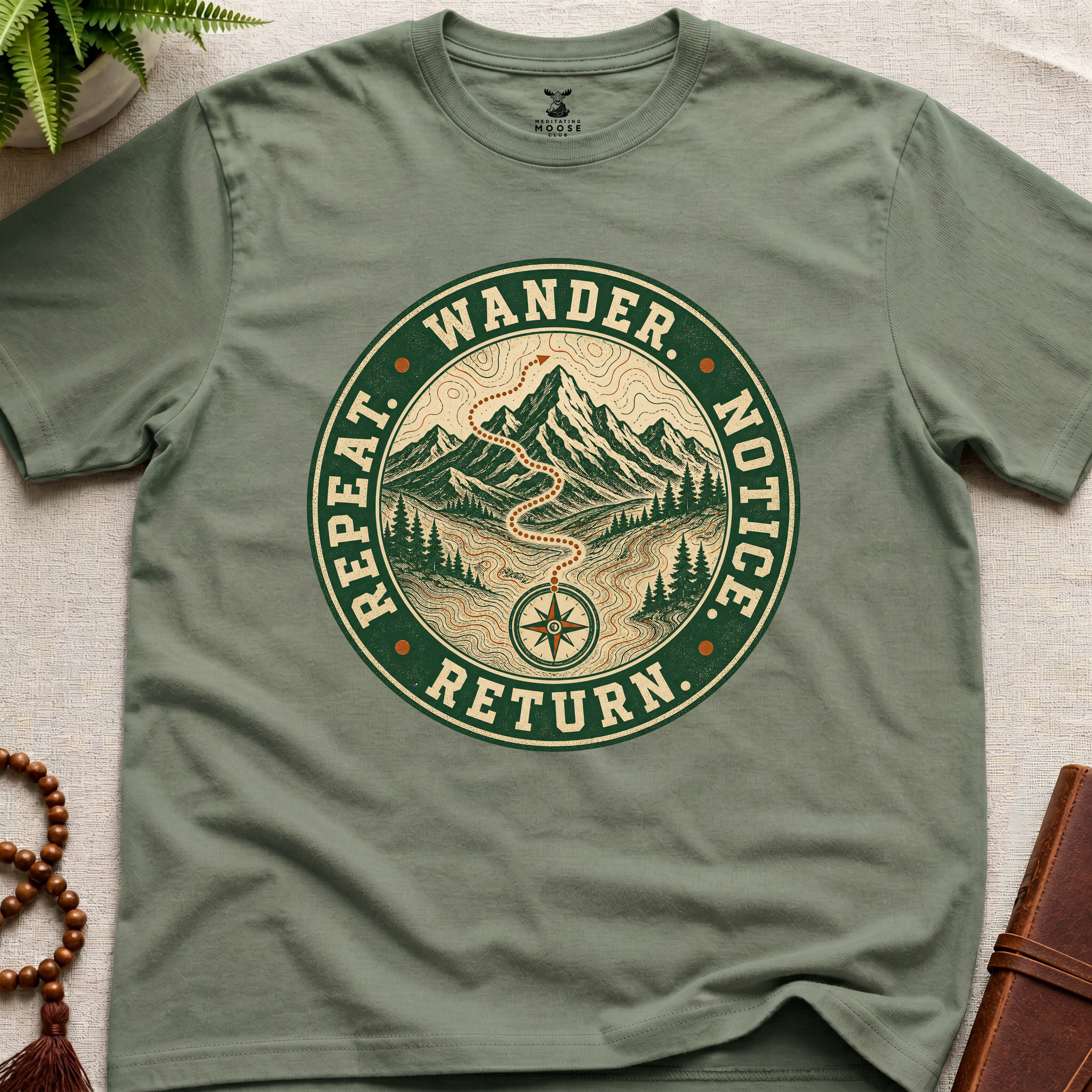 Green mindfulness t-shirt mockup featuring Wander Notice Return vintage mountain meditation badge graphic
